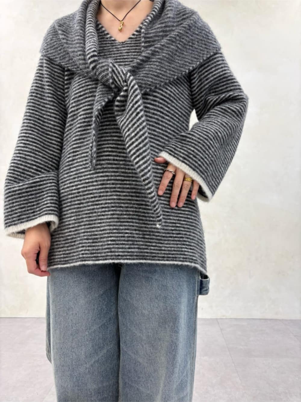 ブルー系のデニムパンツ、ブラック系のブーツ、ブラック系のニット/セーターを着用したレディースの秋コーディネートの4枚目の写真