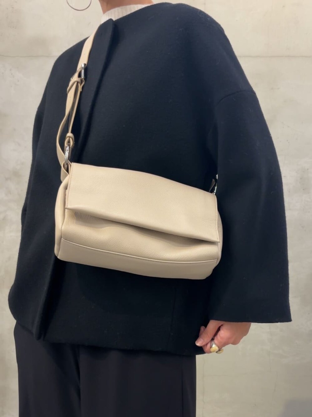 ブラック系のノーカラーコート、ブラック系のその他パンツ、ホワイト系のショルダーバッグを着用したレディースの冬コーディネートの8枚目の写真