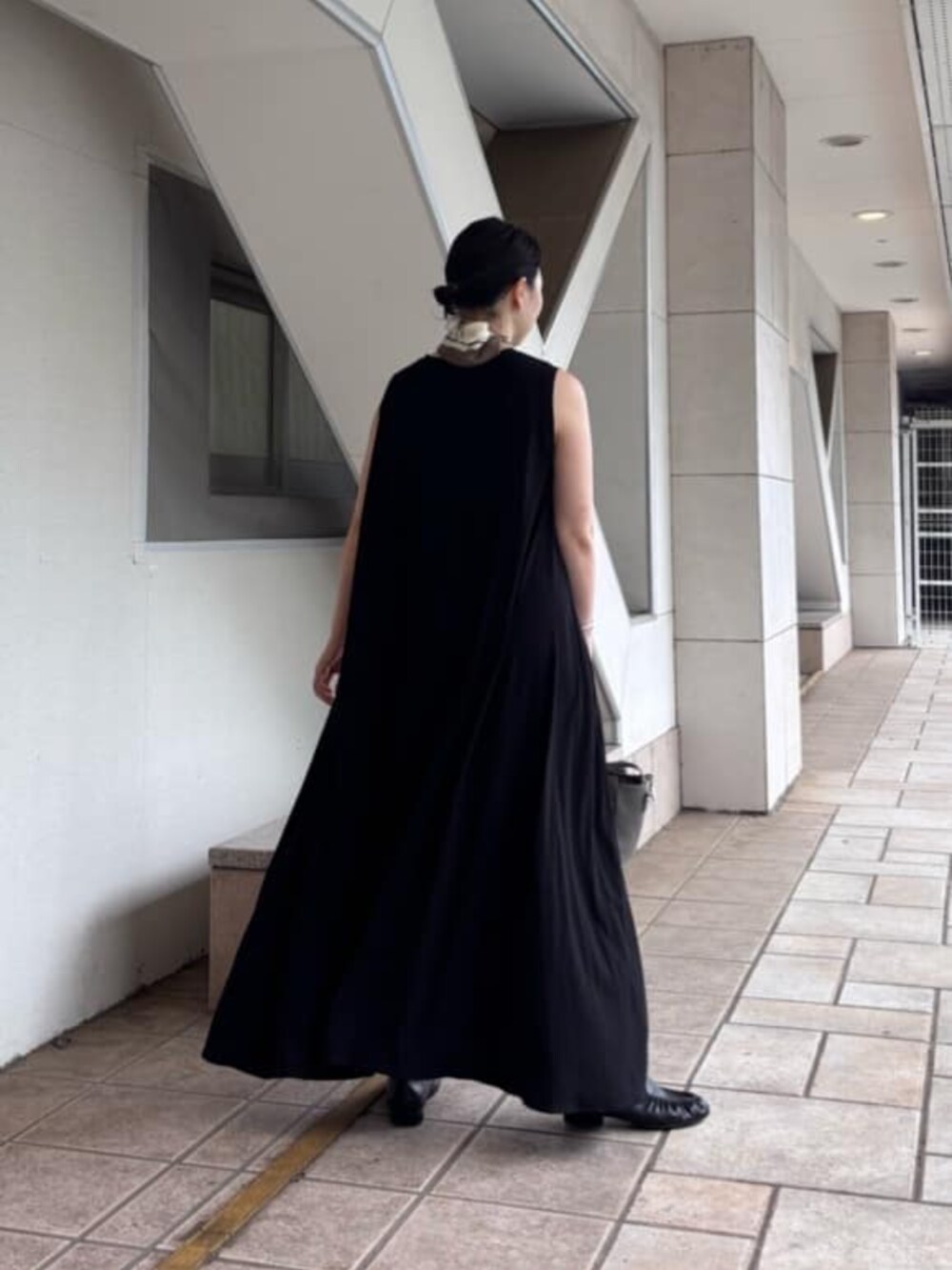 グレー系のハンドバッグ、ブラック系のサンダル、ブラック系のワンピースを着用したレディースの夏コーディネートの3枚目の写真