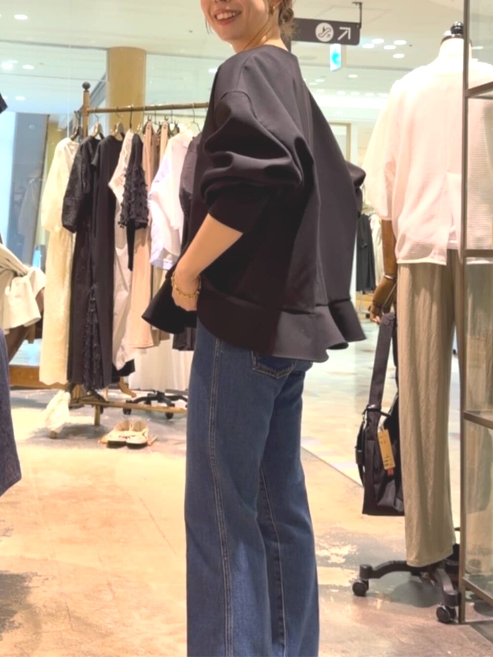 ブラック系のトートバッグ、ブラック系のブルゾン、ブルー系のデニムパンツを着用したレディースの夏コーディネートの5枚目の写真