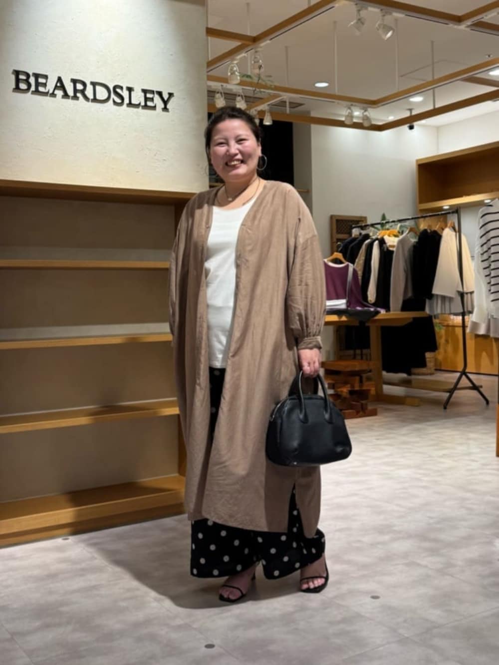 ブラック系のボストンバッグ、ベージュ系のワンピース、ブラック系のその他パンツを着用したレディースの冬コーディネートの3枚目の写真