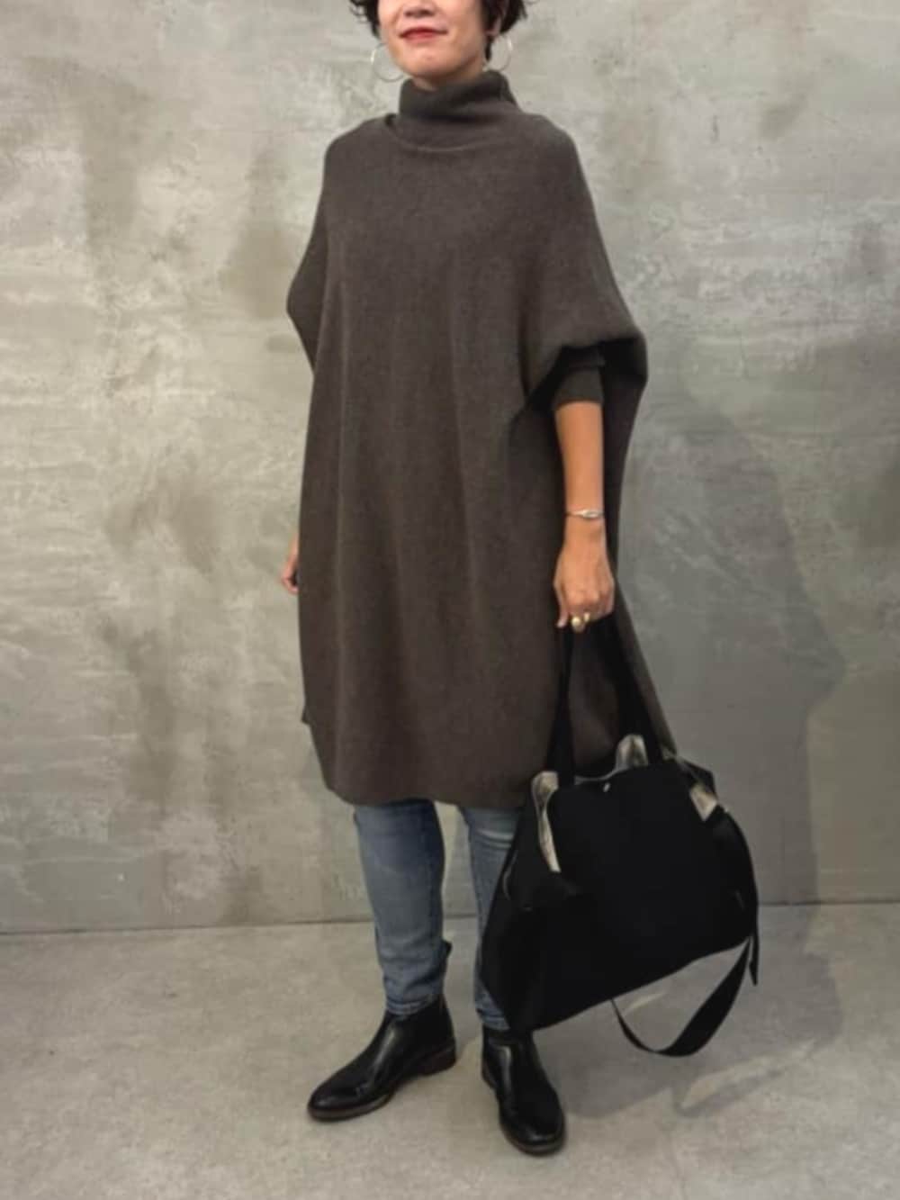 ブルー系のデニムパンツ、ブラウン系のニット/セーター、ブラック系のトートバッグを着用したレディースの秋コーディネートの2枚目の写真