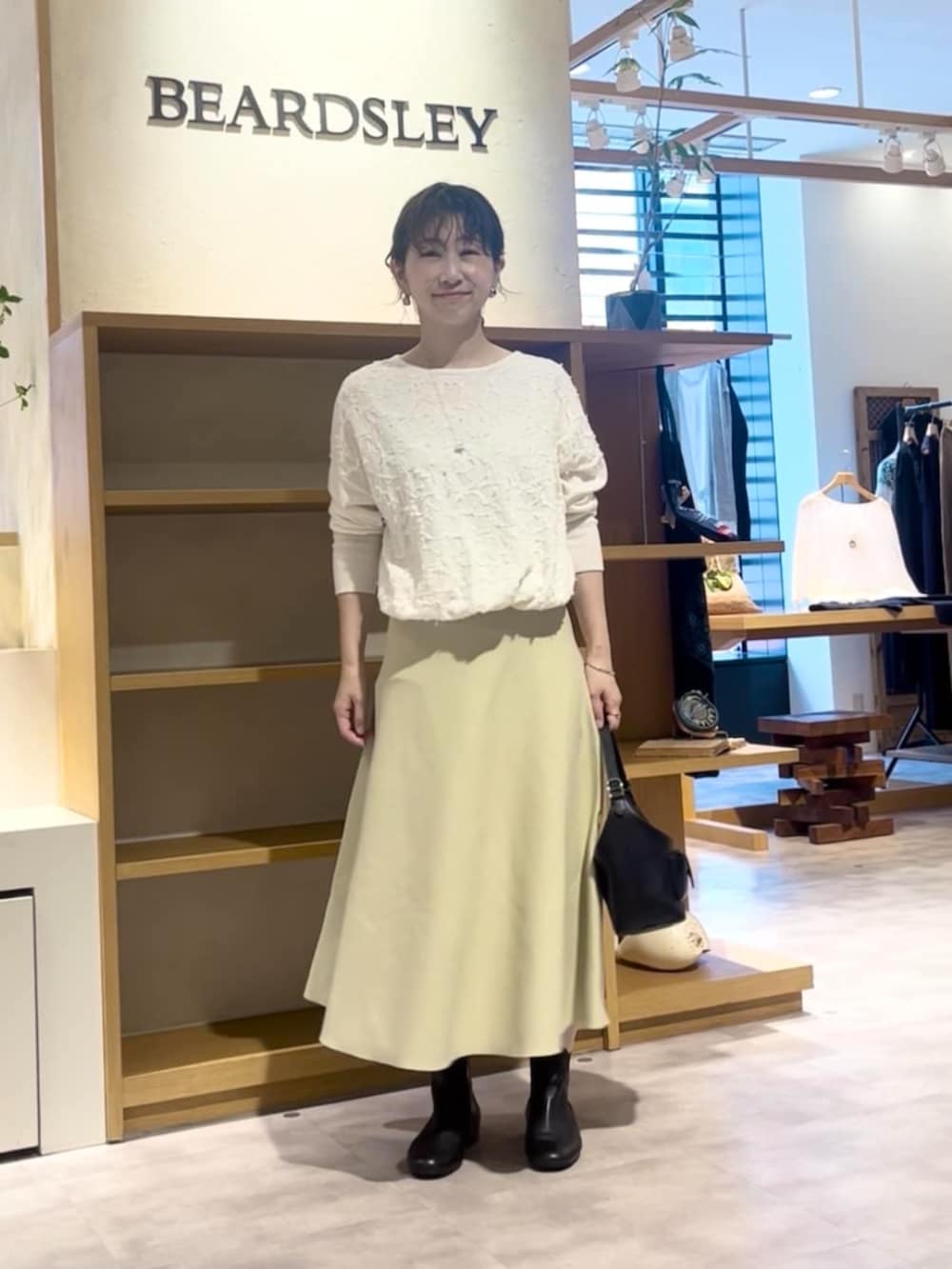 ベージュ系のスカート、ホワイト系のニット/セーターを着用したレディースの夏コーディネートの5枚目の写真