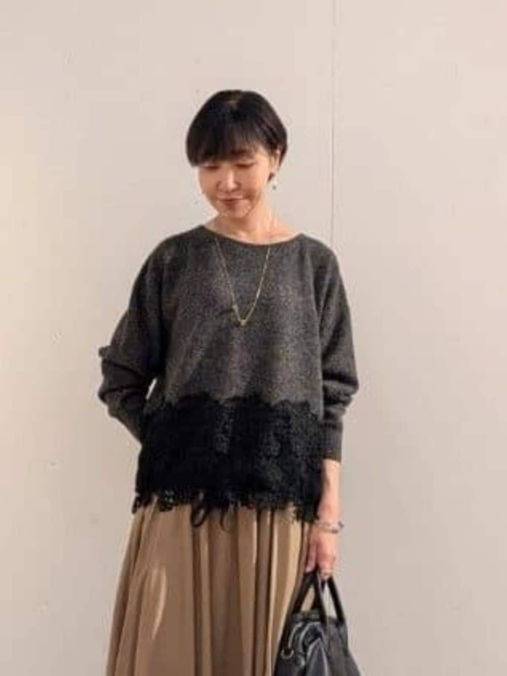 ブラック系のトートバッグ、ブラウン系のスカート、グレー系のニット/セーターを着用したレディースの秋コーディネートの2枚目の写真