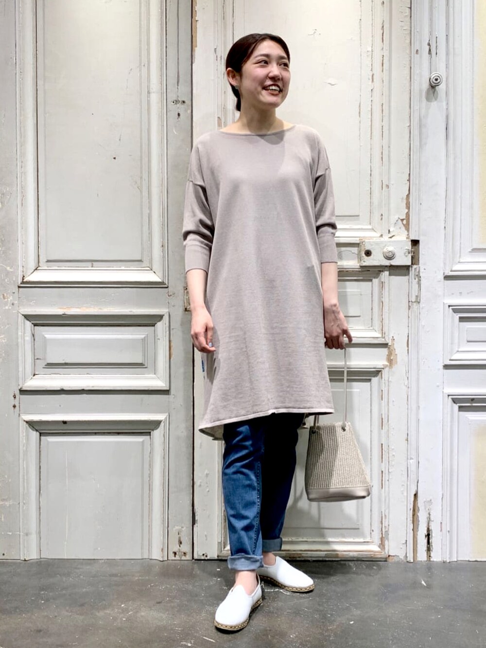 ベージュ系のニット/セーター、ブルー系のデニムパンツ、ベージュ系のトートバッグを着用したレディースの春コーディネートの3枚目の写真