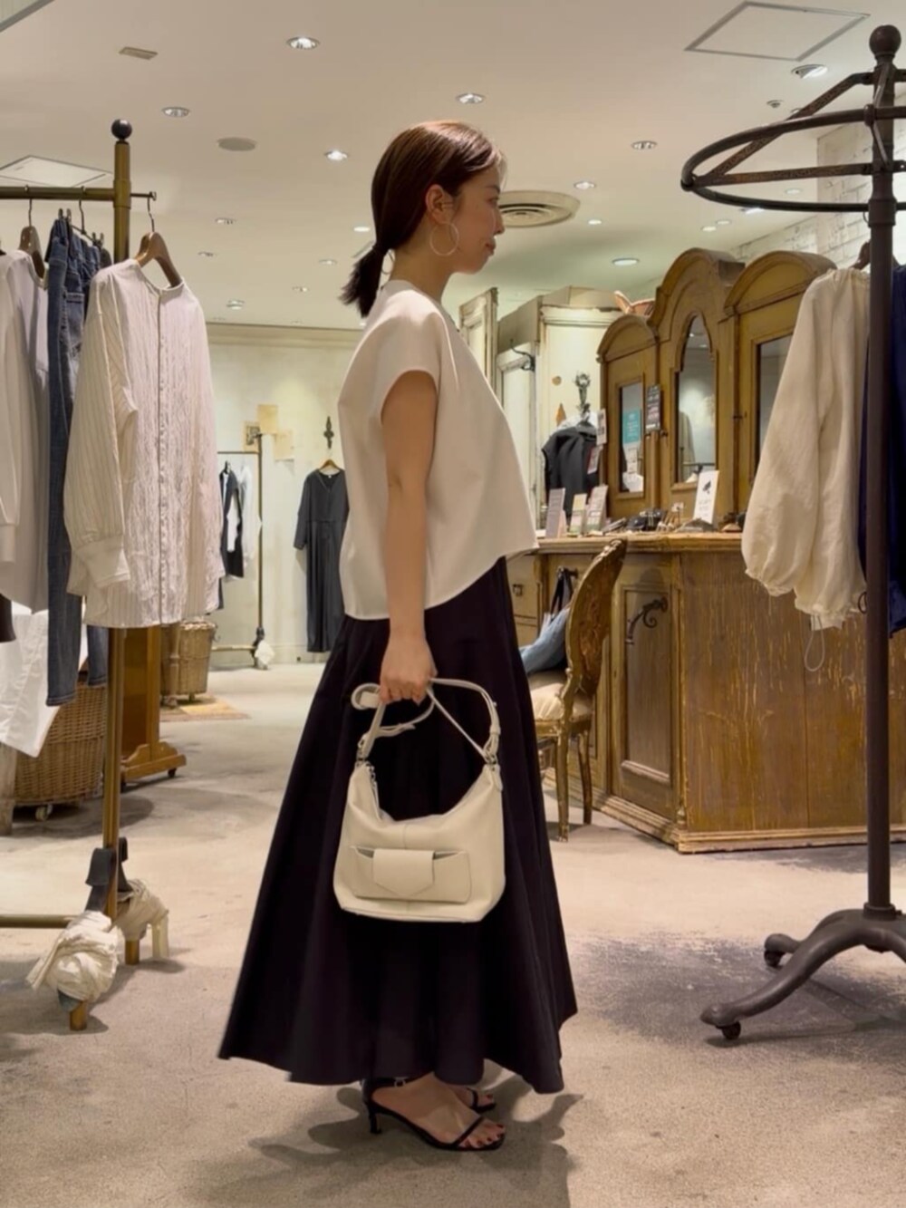 ホワイト系のトートバッグ、ホワイト系のシャツ/ブラウス、ブラック系のスカートを着用したレディースの春コーディネートの2枚目の写真