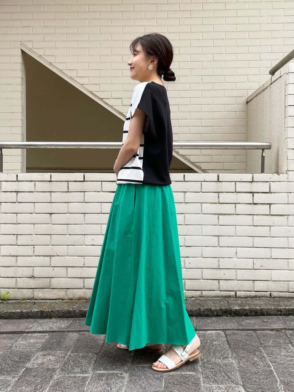 ホワイト系のニット/セーター、グリーン系のスカート、ベージュ系のトートバッグを着用したレディースの夏コーディネートの2枚目の写真