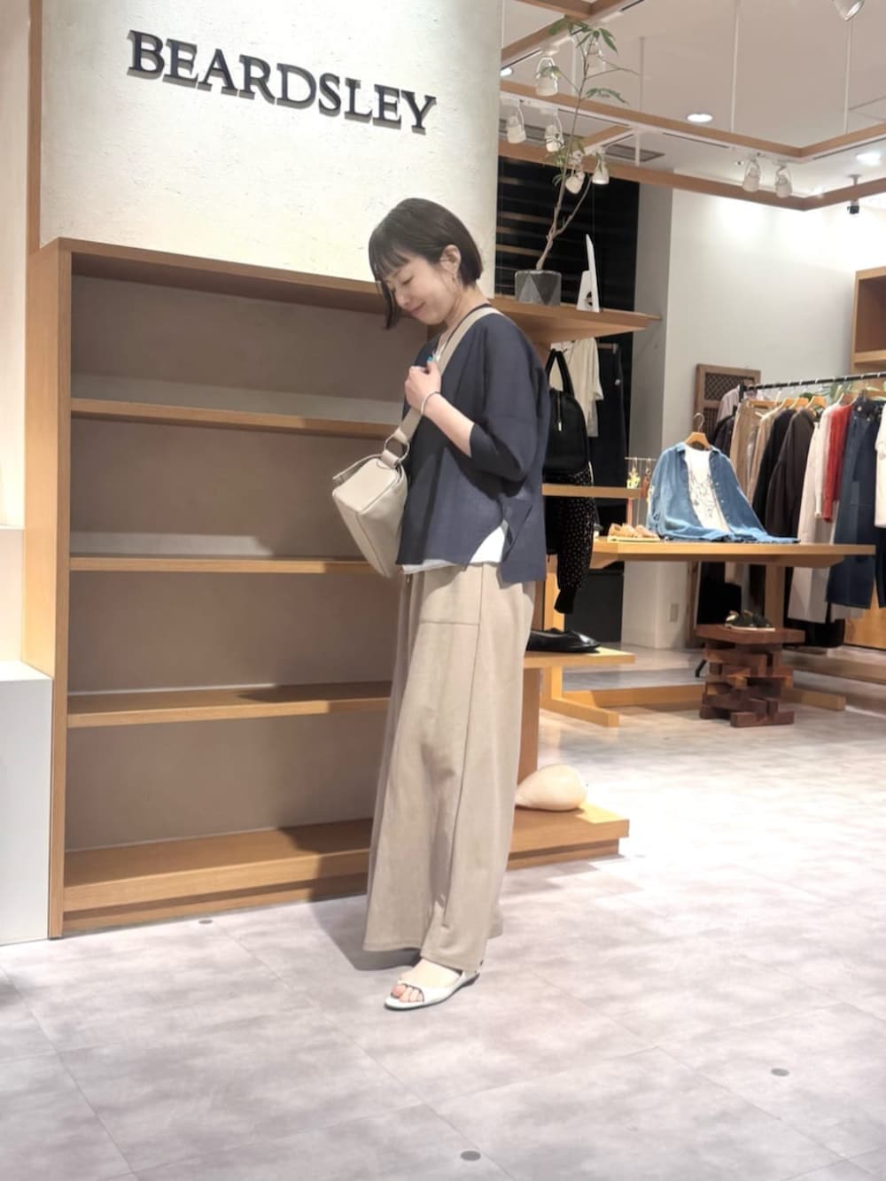 ベージュ系のその他パンツ、ベージュ系のショルダーバッグ、ブルー系のカーディガン/ボレロを着用したレディースの春コーディネートの2枚目の写真