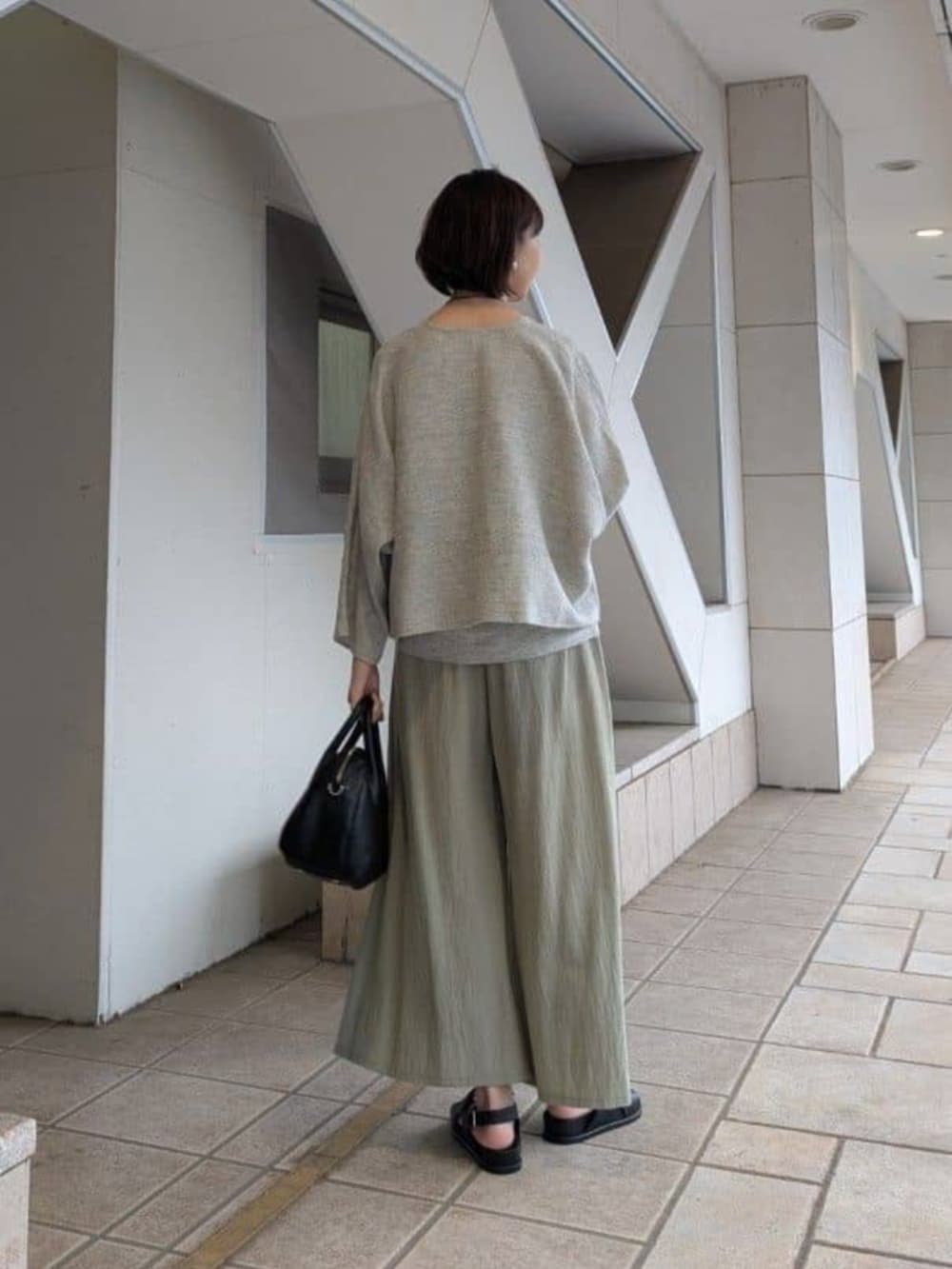 グリーン系のその他パンツ、ブラック系のサンダル、グレー系のニット/セーターを着用したレディースの冬コーディネートの3枚目の写真