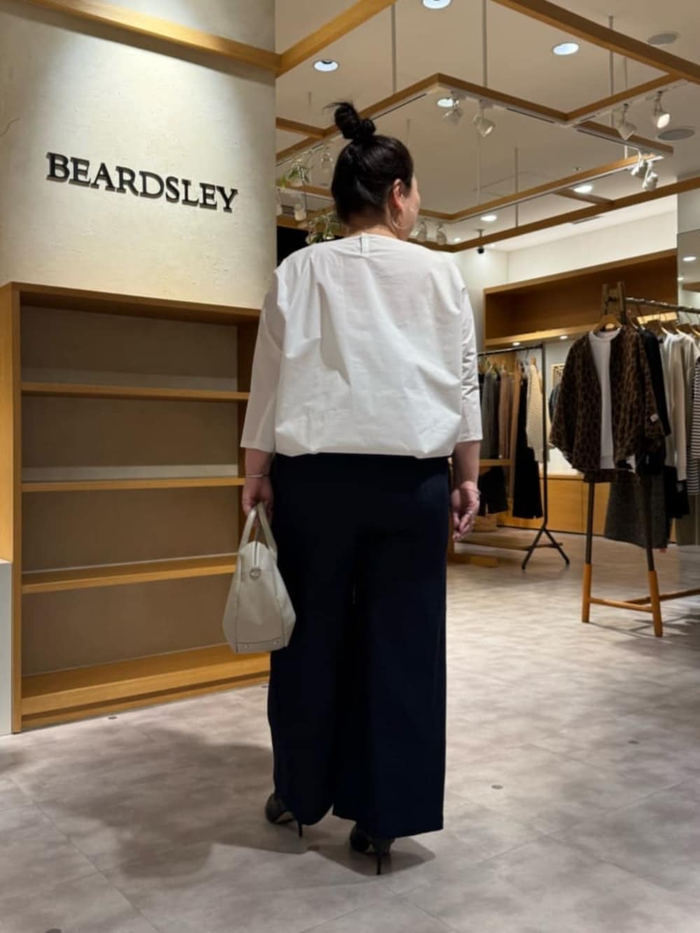 グレー系のボストンバッグ、ブラック系のブーツ、ホワイト系のシャツ/ブラウスを着用したレディースの冬コーディネートの6枚目の写真