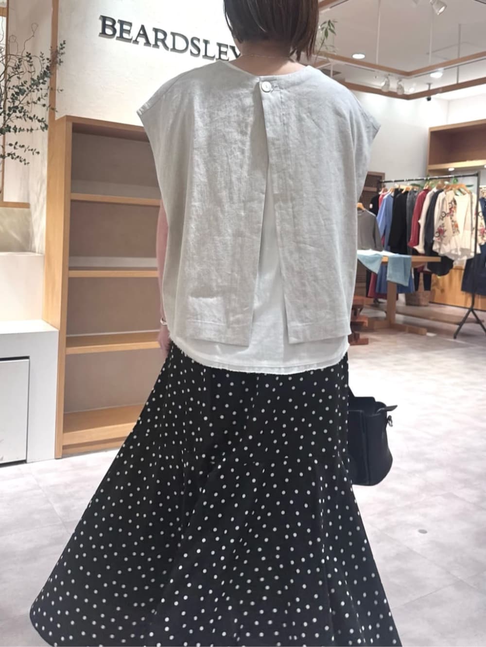 ブラック系のハンドバッグ、ブラック系のスカート、ベージュ系のシャツ/ブラウスを着用したレディースの春コーディネートの9枚目の写真