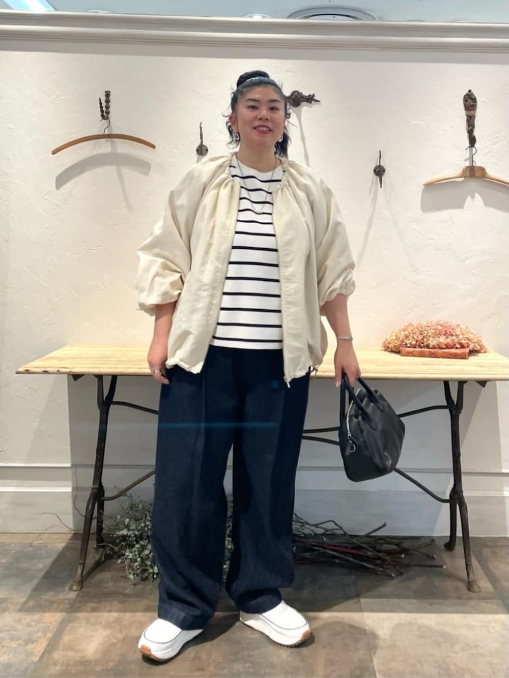 ホワイト系のノーカラージャケット、ホワイト系のニット/セーター、ブルー系のデニムパンツを着用したレディースの冬コーディネートの2枚目の写真