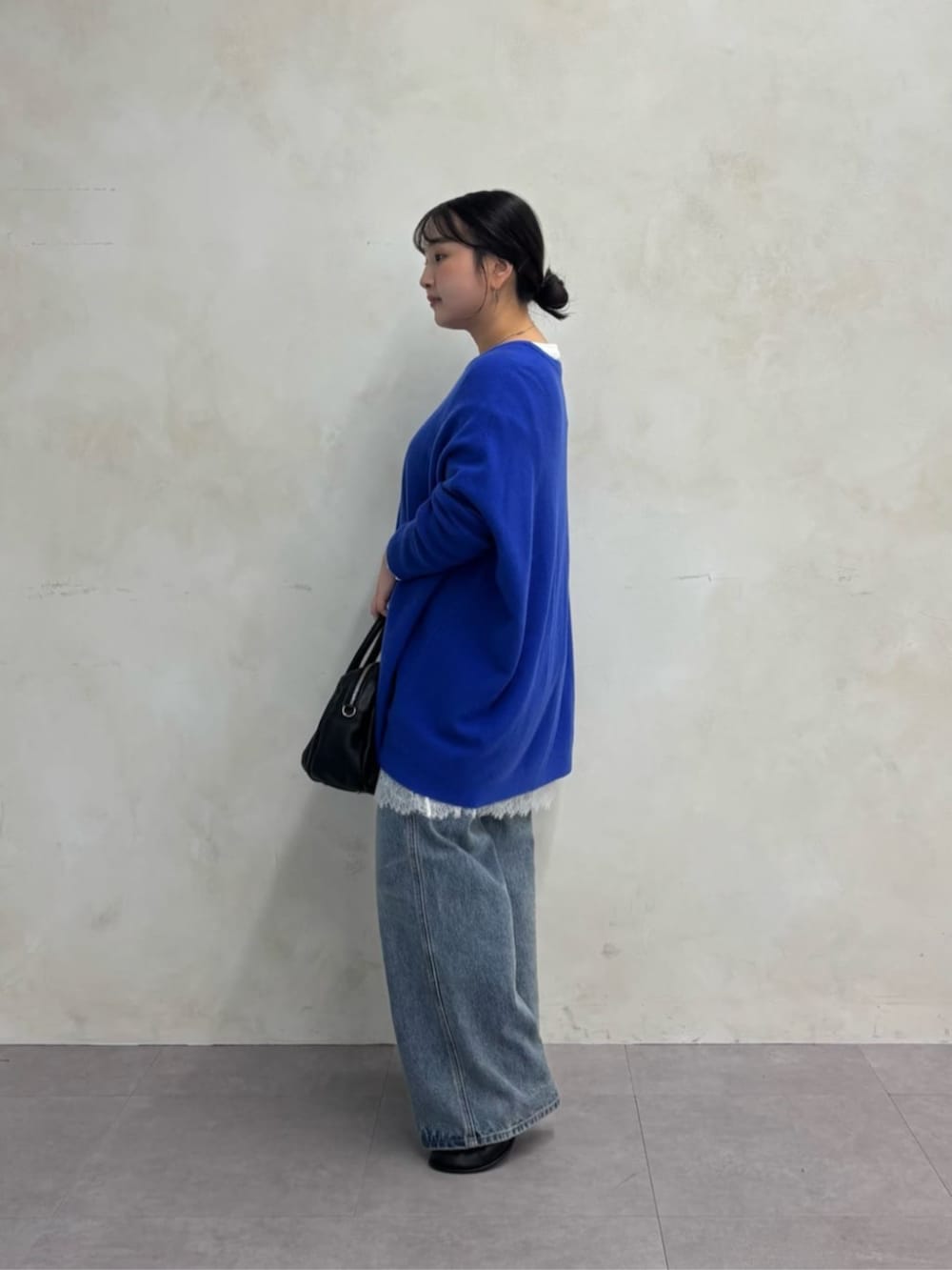 ブラック系のトートバッグ、ブルー系のデニムパンツ、ブラック系のブーツを着用したレディースの秋コーディネートの6枚目の写真