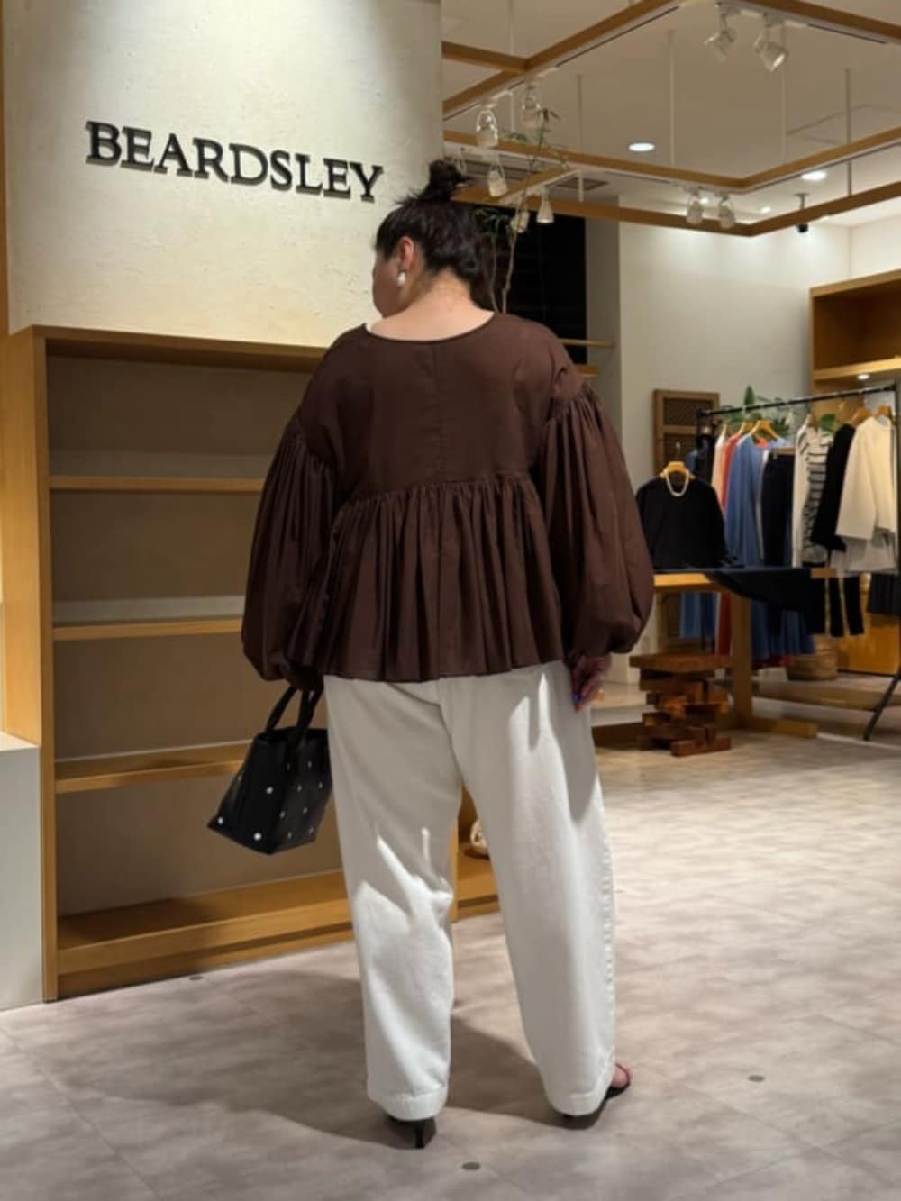 ブラック系のトートバッグ、ホワイト系のデニムパンツ、ブラウン系のシャツ/ブラウスを着用したレディースの冬コーディネートの5枚目の写真