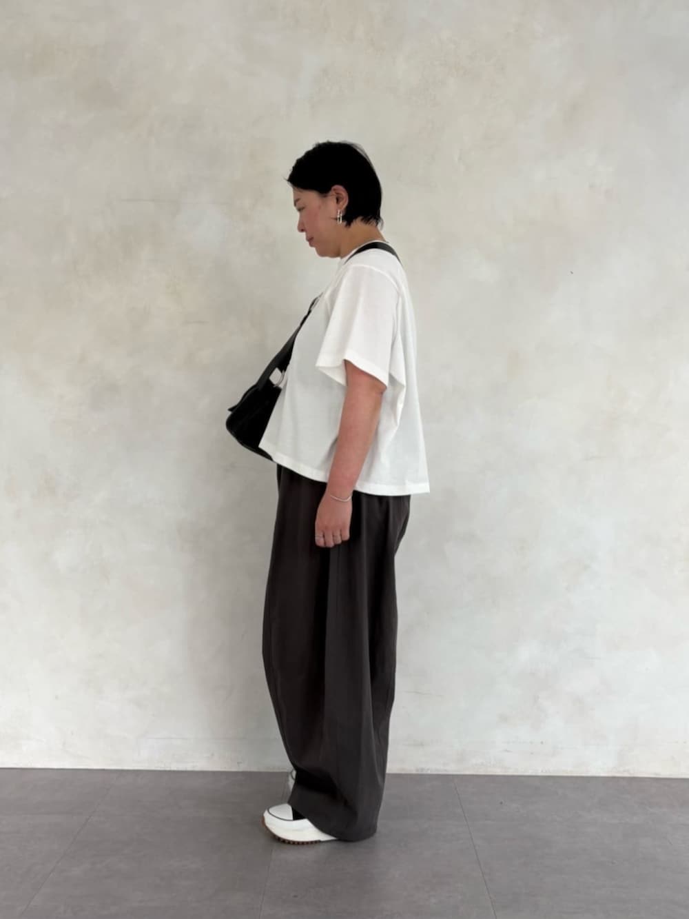 ブラック系のショルダーバッグ、グレー系のその他パンツ、ホワイト系のTシャツ/カットソーを着用したレディースの春コーディネートの3枚目の写真