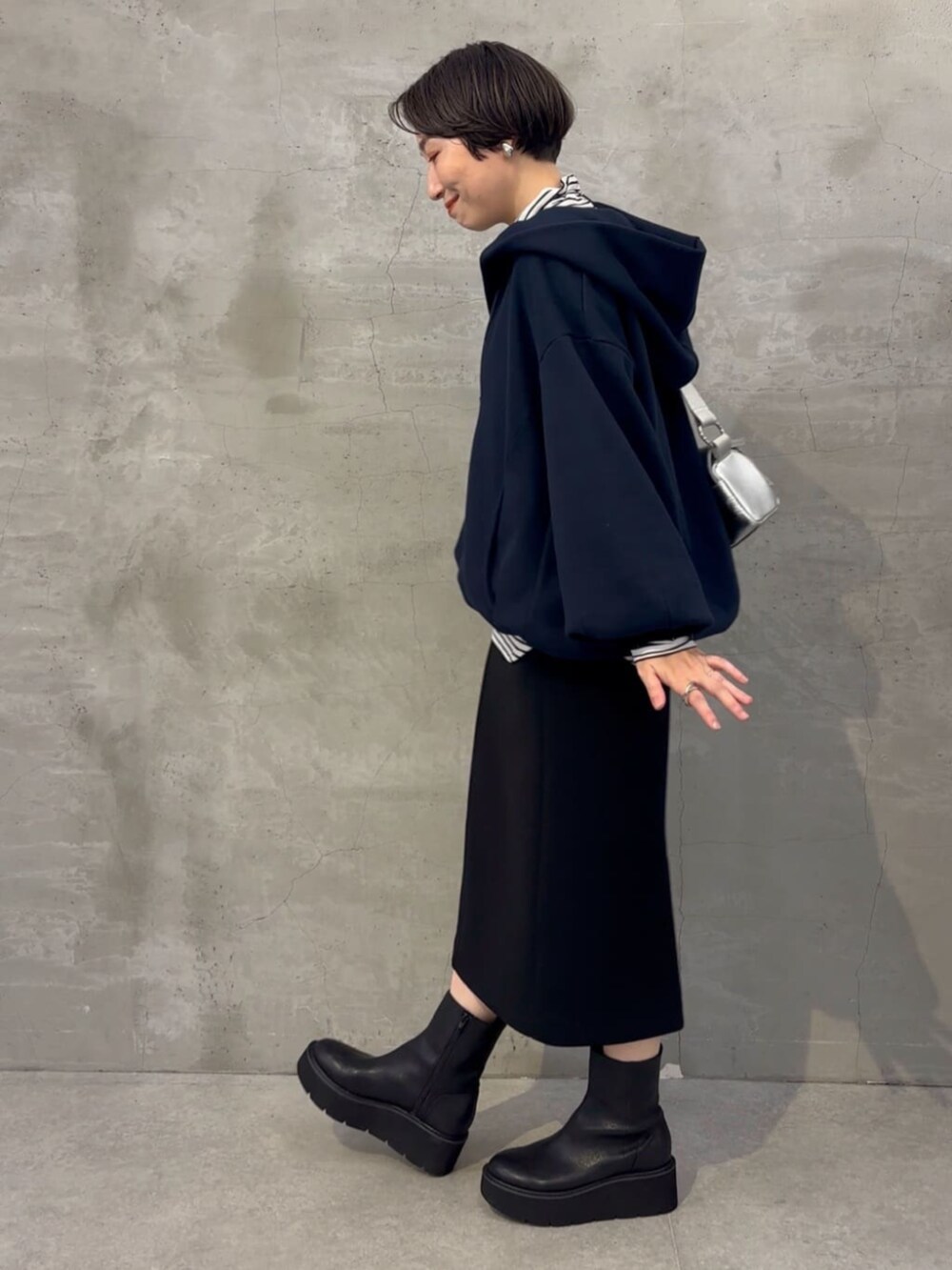 ブラック系のブーツ、ブラック系のスカート、ブルー系のパーカーを着用したレディースの冬コーディネートの5枚目の写真