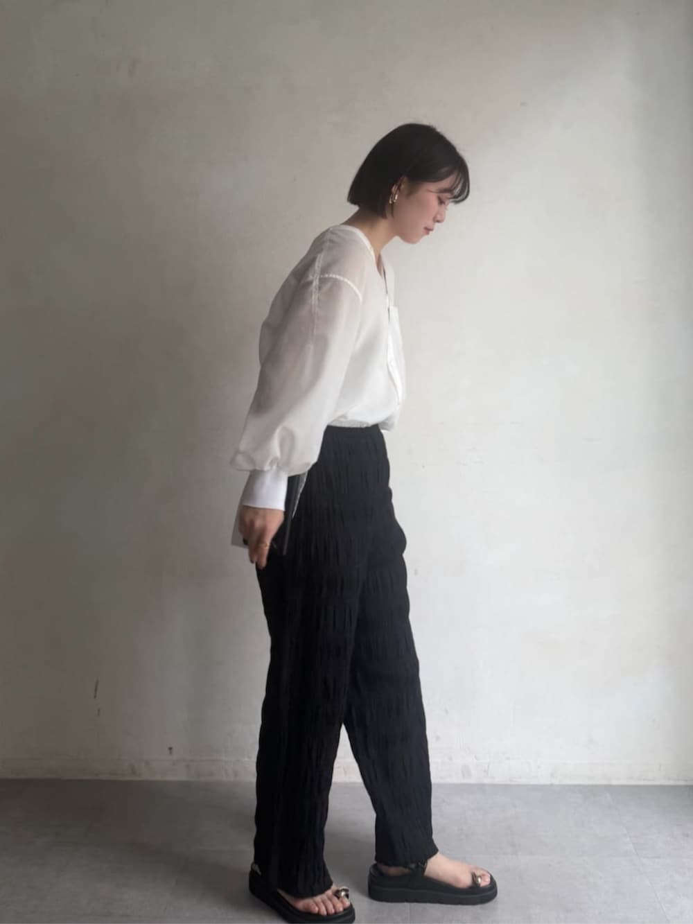 ブラック系のその他パンツ、ブラック系のサンダル、ホワイト系のシャツ/ブラウスを着用したレディースの冬コーディネートの2枚目の写真