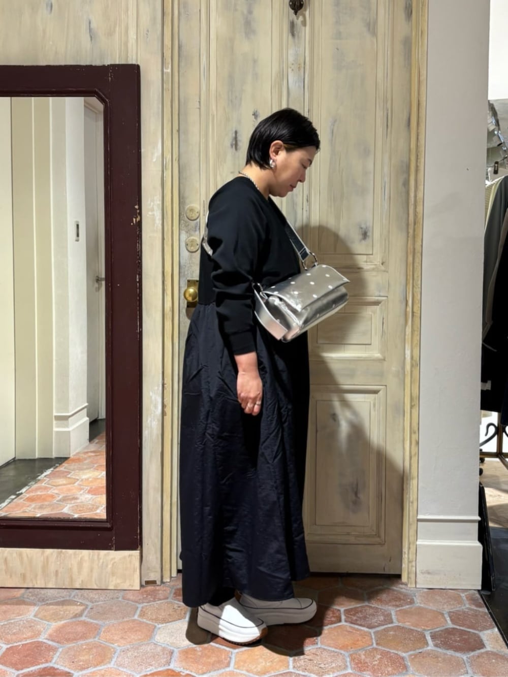 ホワイト系のスニーカー、ブラック系のワンピース、シルバー系のショルダーバッグを着用したレディースの冬コーディネートの3枚目の写真