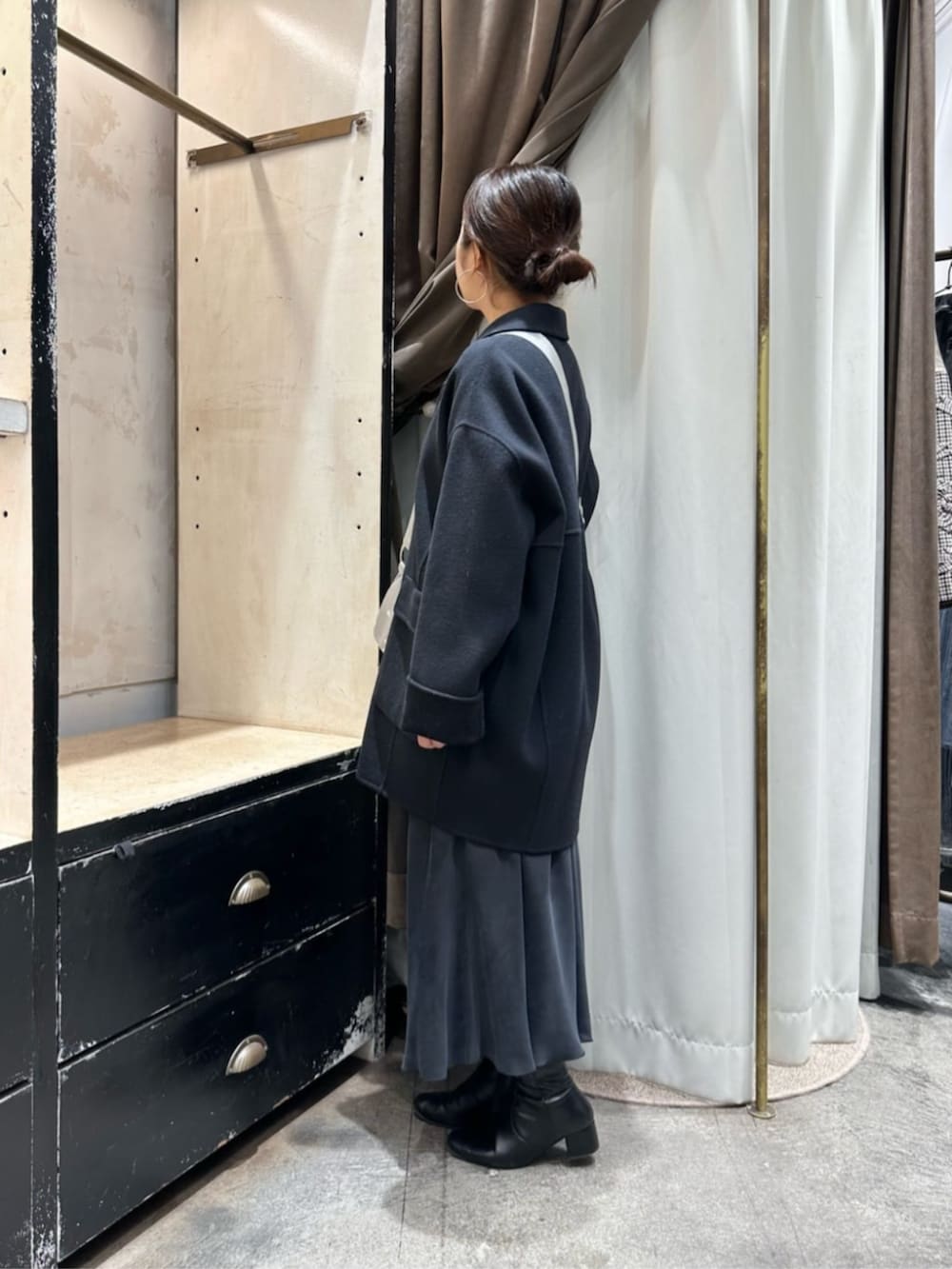 ブラック系のスカート、ブルー系のピーコート、シルバー系のショルダーバッグを着用したレディースの冬コーディネートの2枚目の写真