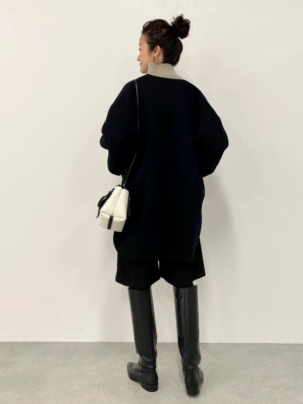 ブラック系のその他パンツ、ブラック系のノーカラーコート、グリーン系のニット/セーターを着用したレディースの秋コーディネートの2枚目の写真