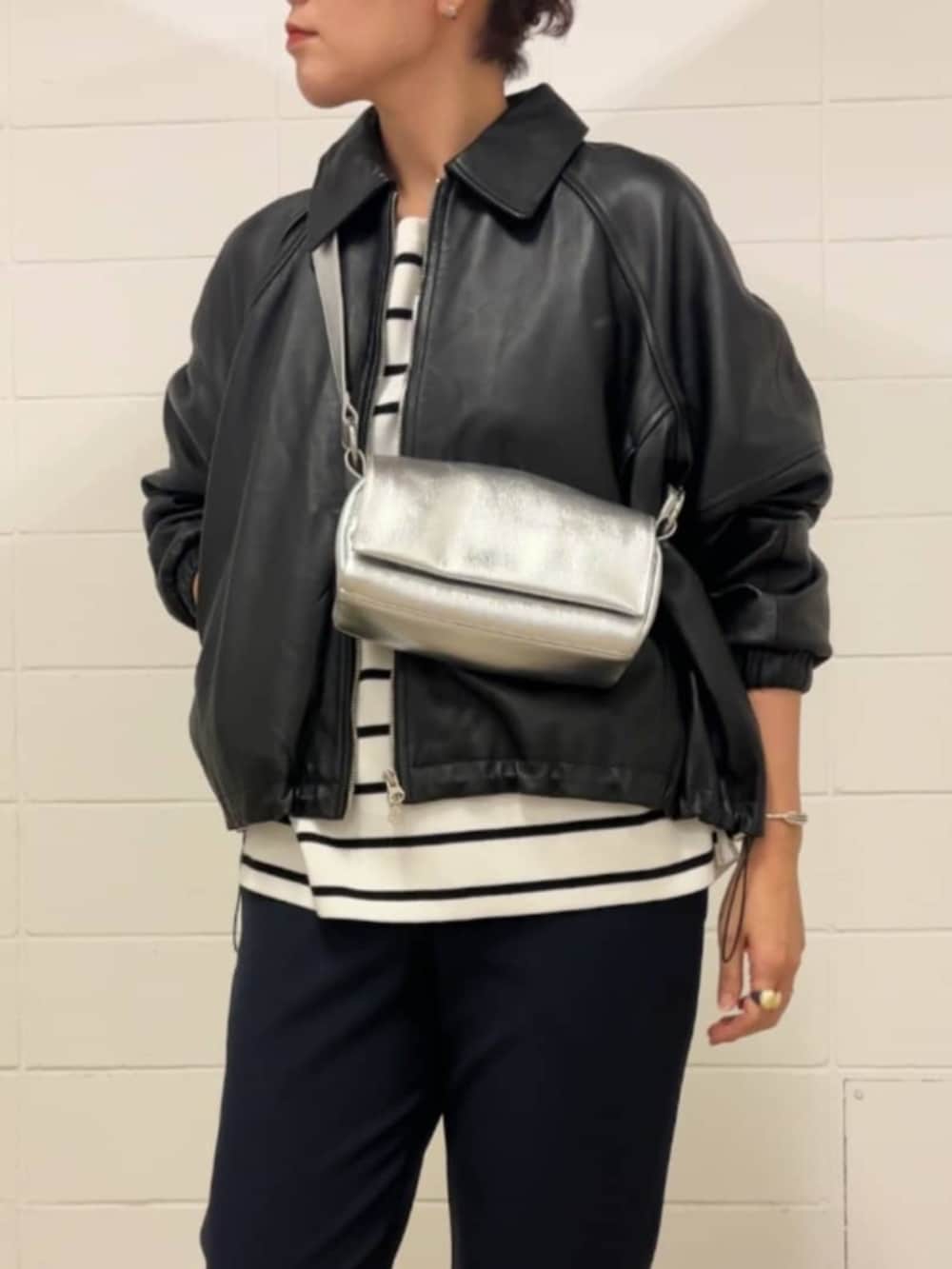 シルバー系のショルダーバッグ、ホワイト系のニット/セーター、ブラック系のブルゾンを着用したレディースの冬コーディネートの4枚目の写真