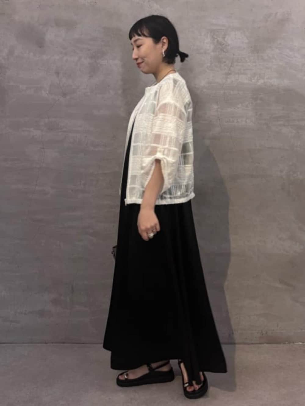 グレー系のハンドバッグ、ブラック系のワンピース、ホワイト系のブルゾンを着用したレディースの夏コーディネートの3枚目の写真