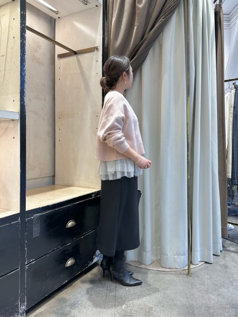 ブラック系のスカート、ブラック系のブーツ、ホワイト系のタンクトップを着用したレディースの冬コーディネートの2枚目の写真