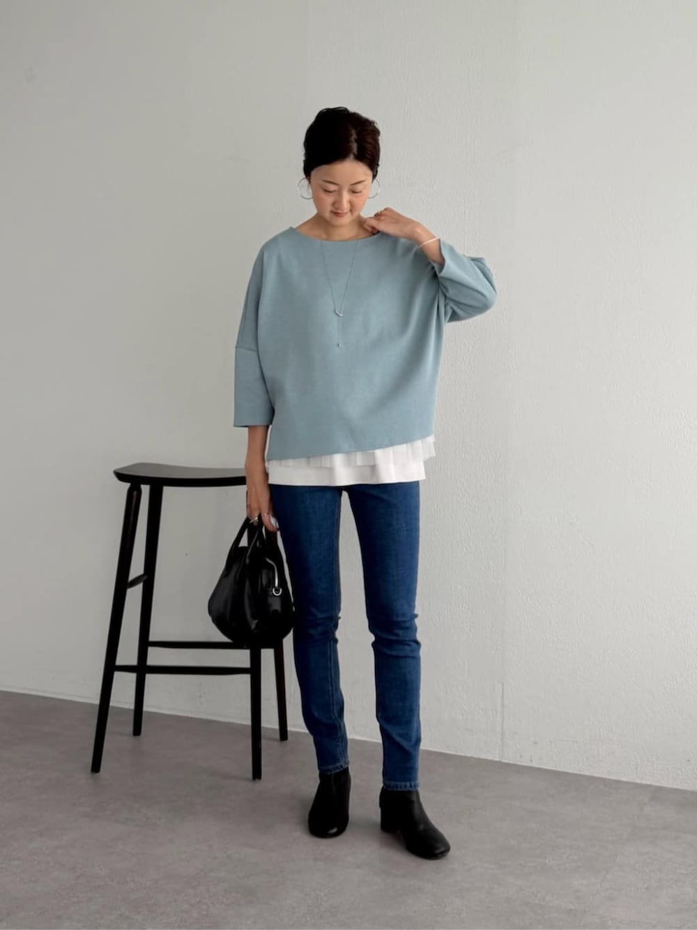 ブルー系のデニムパンツ、ブルー系のニット/セーター、ホワイト系のキャミソールを着用したレディースの夏コーディネートの4枚目の写真