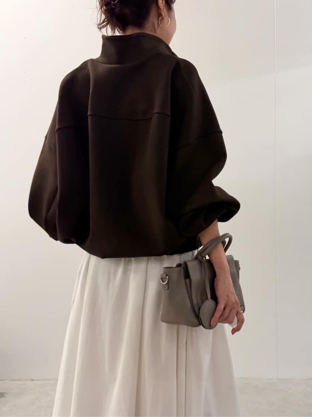 グレー系のハンドバッグ、ホワイト系のスカート、ブラウン系のTシャツ/カットソーを着用したレディースの夏コーディネートの5枚目の写真