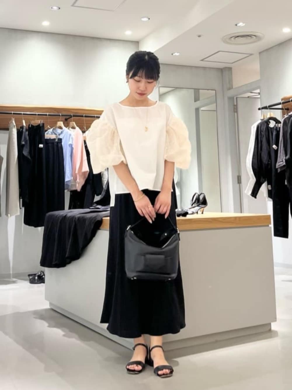 ブラック系のスカート、ホワイト系のシャツ/ブラウスを着用したレディースの夏コーディネートの5枚目の写真