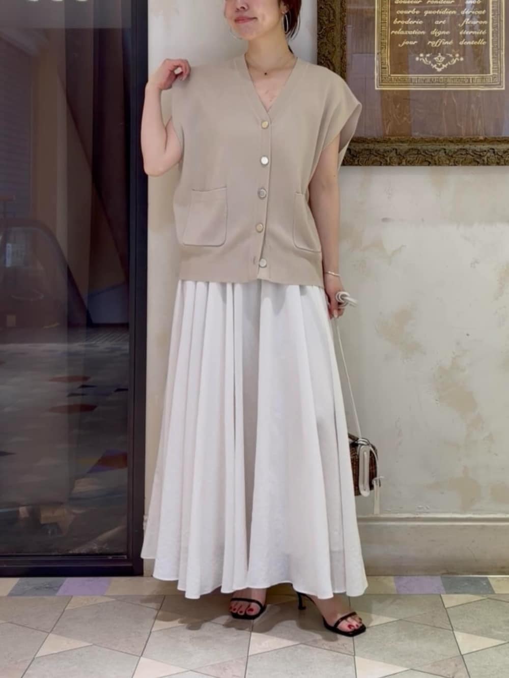 ホワイト系のスカート、ベージュ系のカーディガン/ボレロを着用したレディースの春コーディネートの4枚目の写真