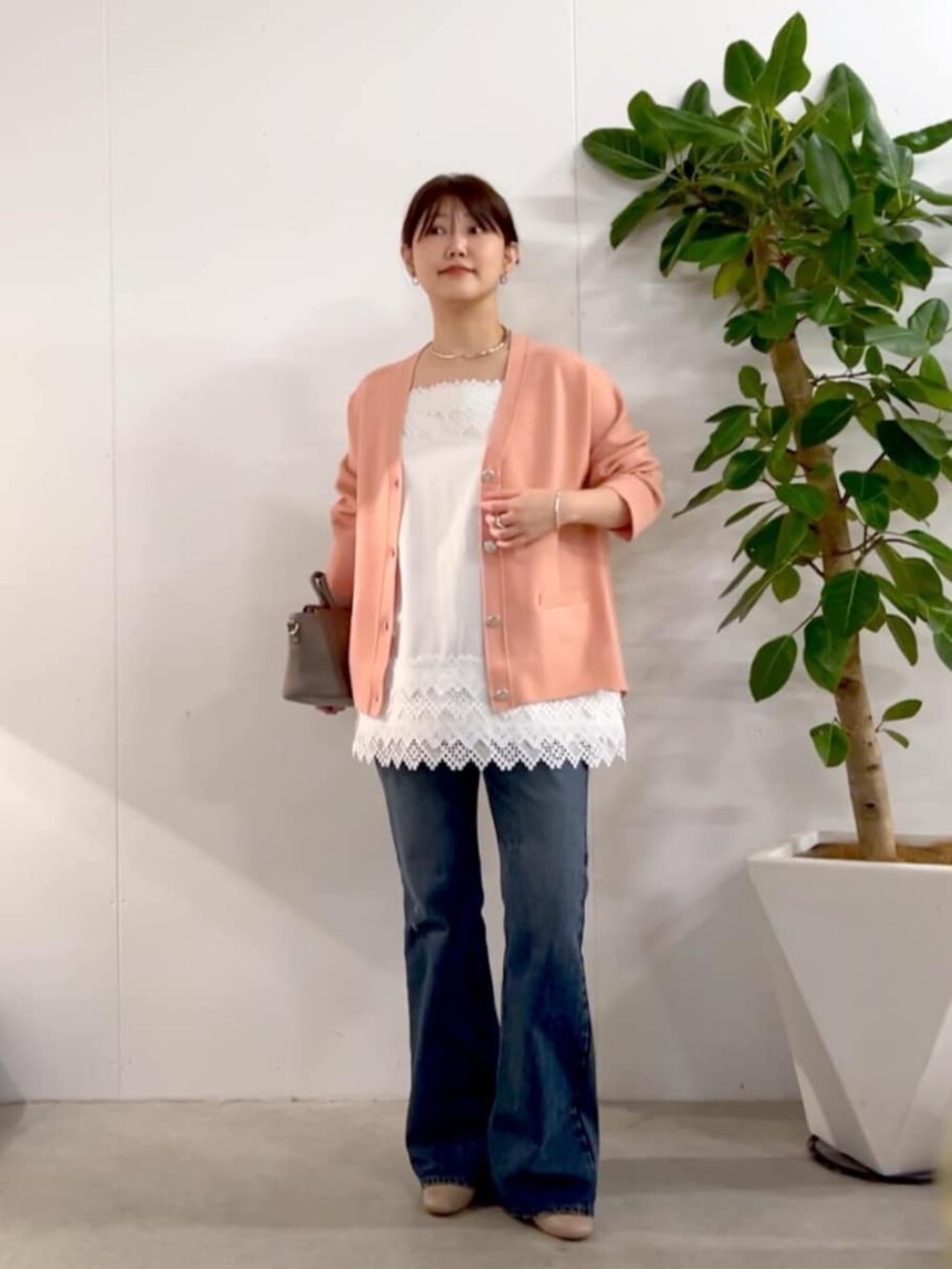 グレー系のハンドバッグ、ピンク系のニット/セーター、ホワイト系のキャミソールを着用したレディースの秋コーディネートの2枚目の写真