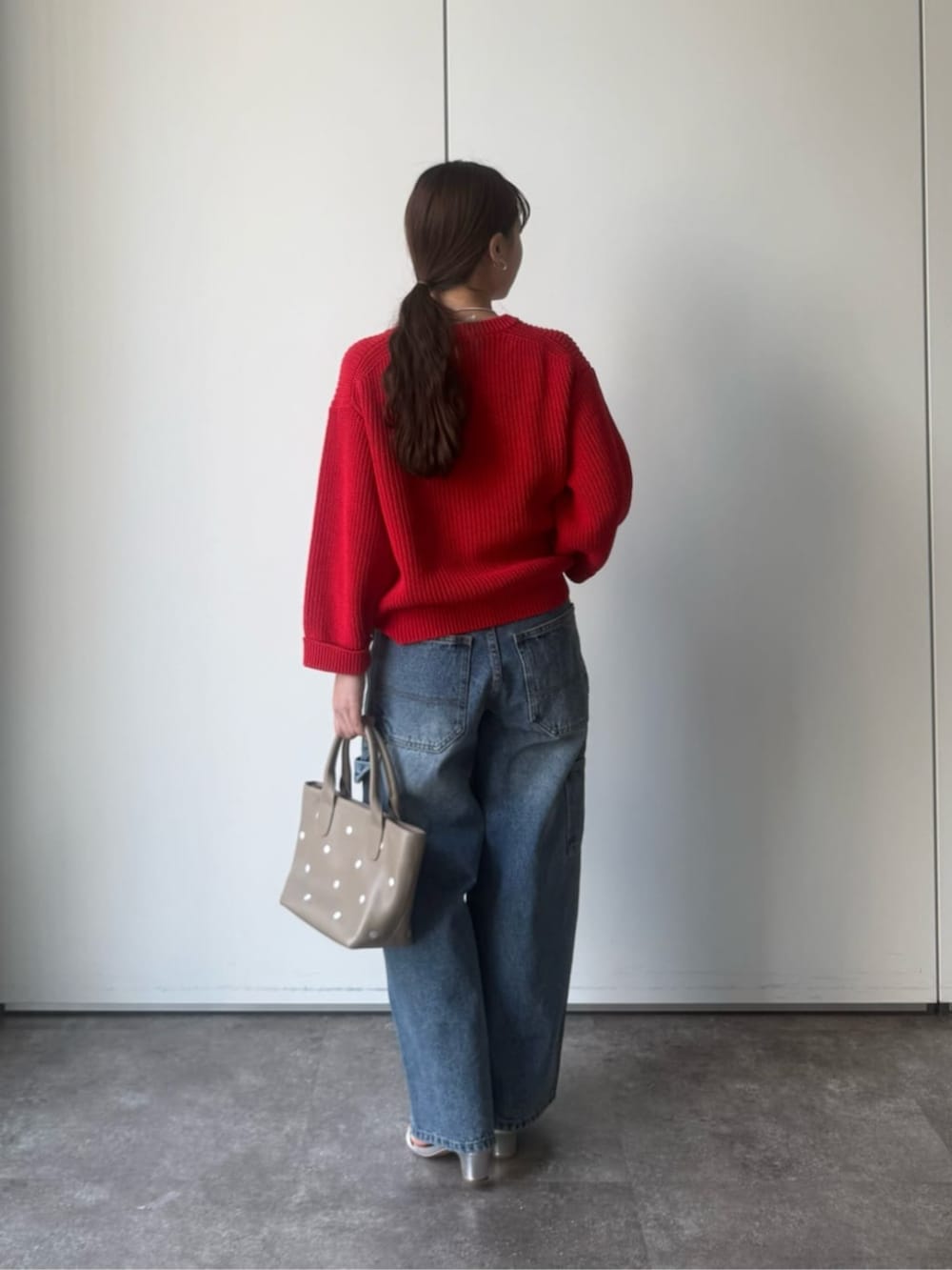レッド系のニット/セーター、グレー系のトートバッグを着用したレディースの冬コーディネートの3枚目の写真