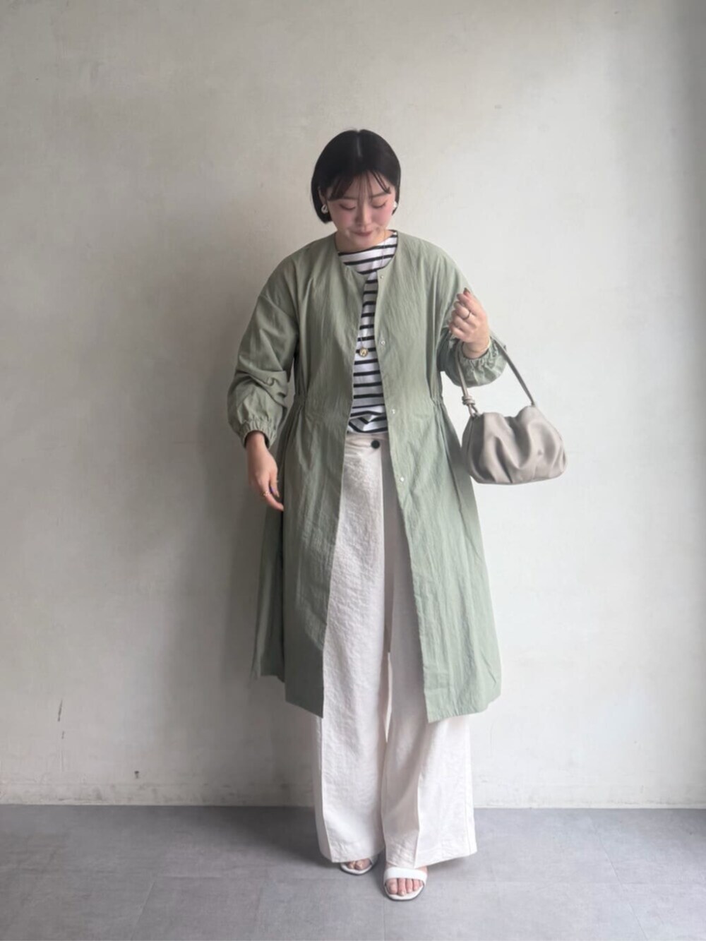 ベージュ系のショルダーバッグ、グリーン系のその他アウター、ホワイト系のその他パンツを着用したレディースの冬コーディネートの2枚目の写真