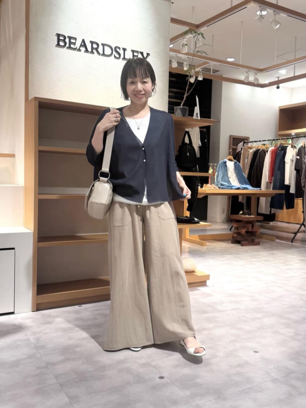 ベージュ系のその他パンツ、ベージュ系のショルダーバッグ、ブルー系のカーディガン/ボレロを着用したレディースの春コーディネートの7枚目の写真