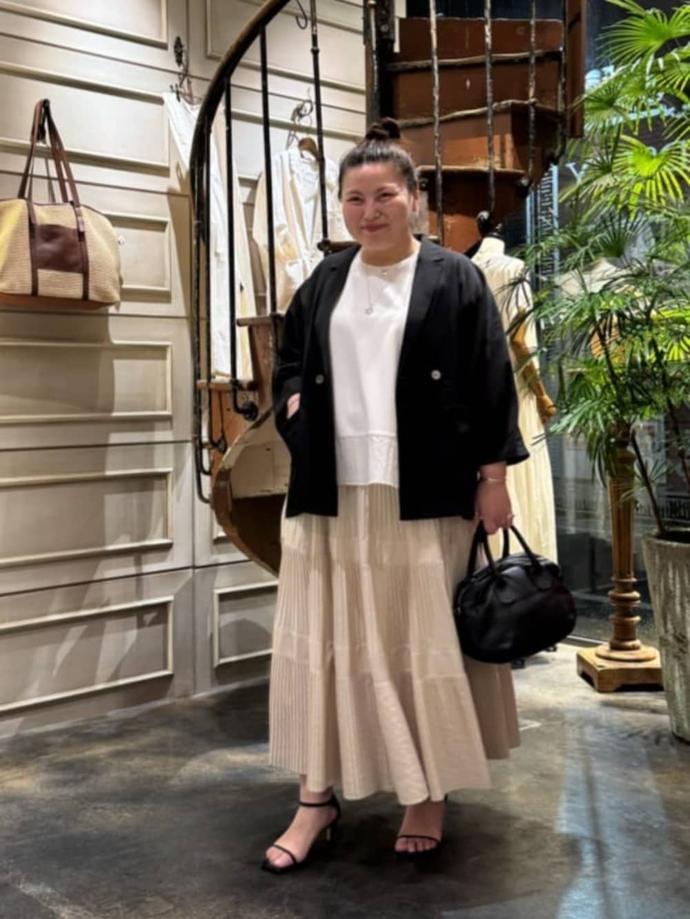 ホワイト系のスカート、ブラック系のテーラードジャケットを着用したレディースの春コーディネートの2枚目の写真