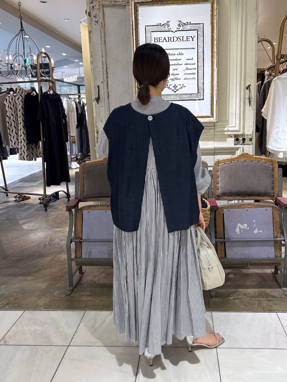 ブルー系のベスト、ブルー系のワンピース、グレー系のショルダーバッグを着用したレディースの夏コーディネートの3枚目の写真