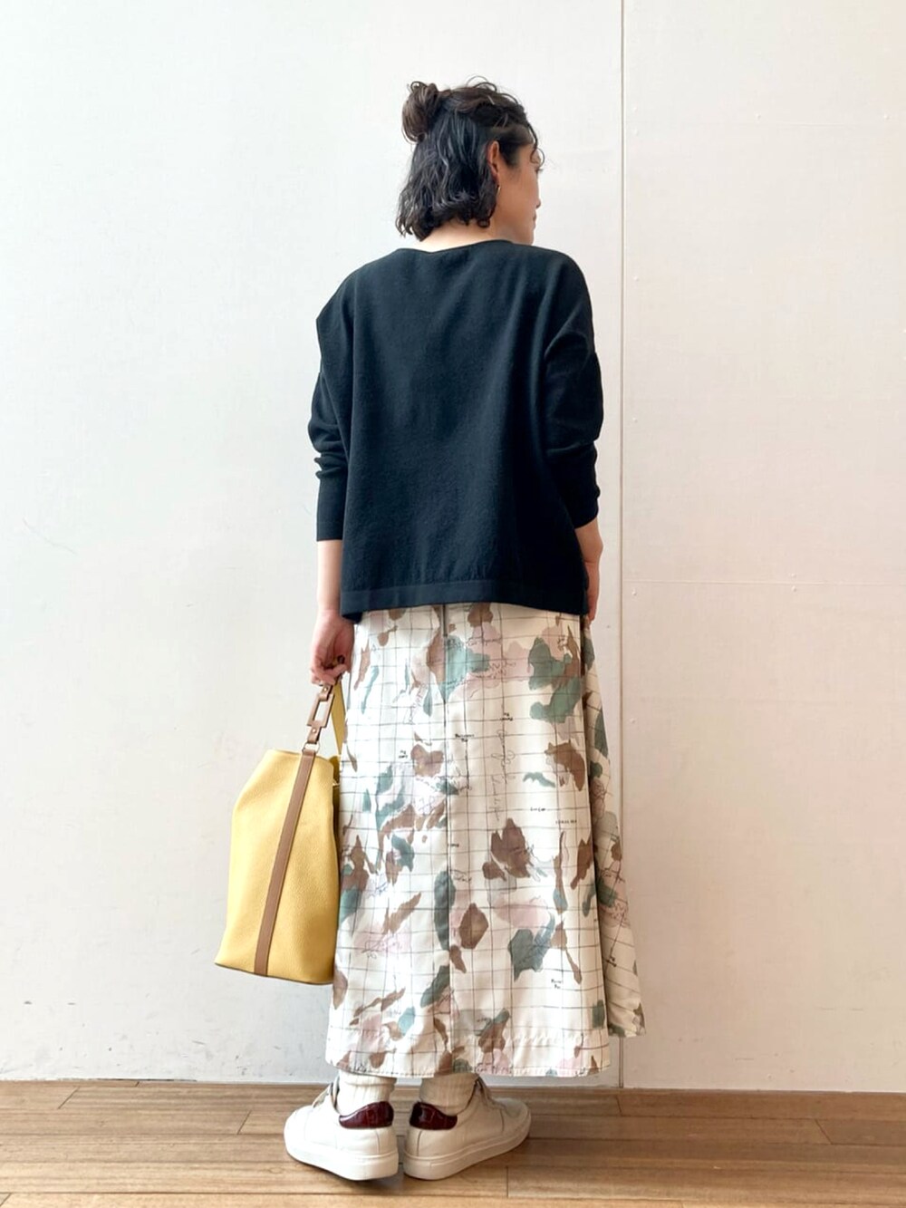 ブラック系のニット/セーター、ホワイト系のスカート、イエロー系のトートバッグを着用したレディースの春コーディネートの3枚目の写真