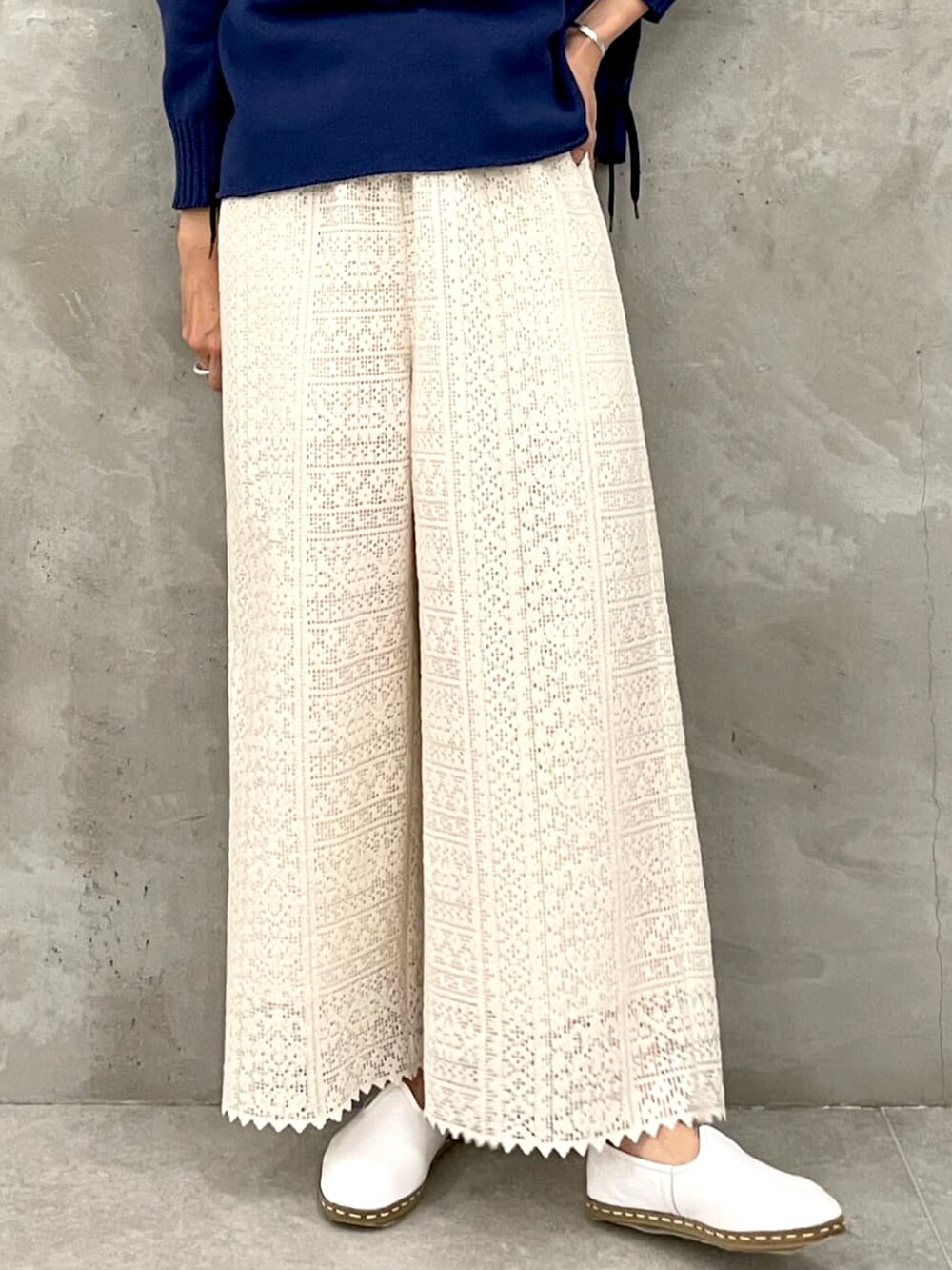 ブルー系のニット/セーター、ホワイト系のその他パンツを着用したレディースの春コーディネートの2枚目の写真