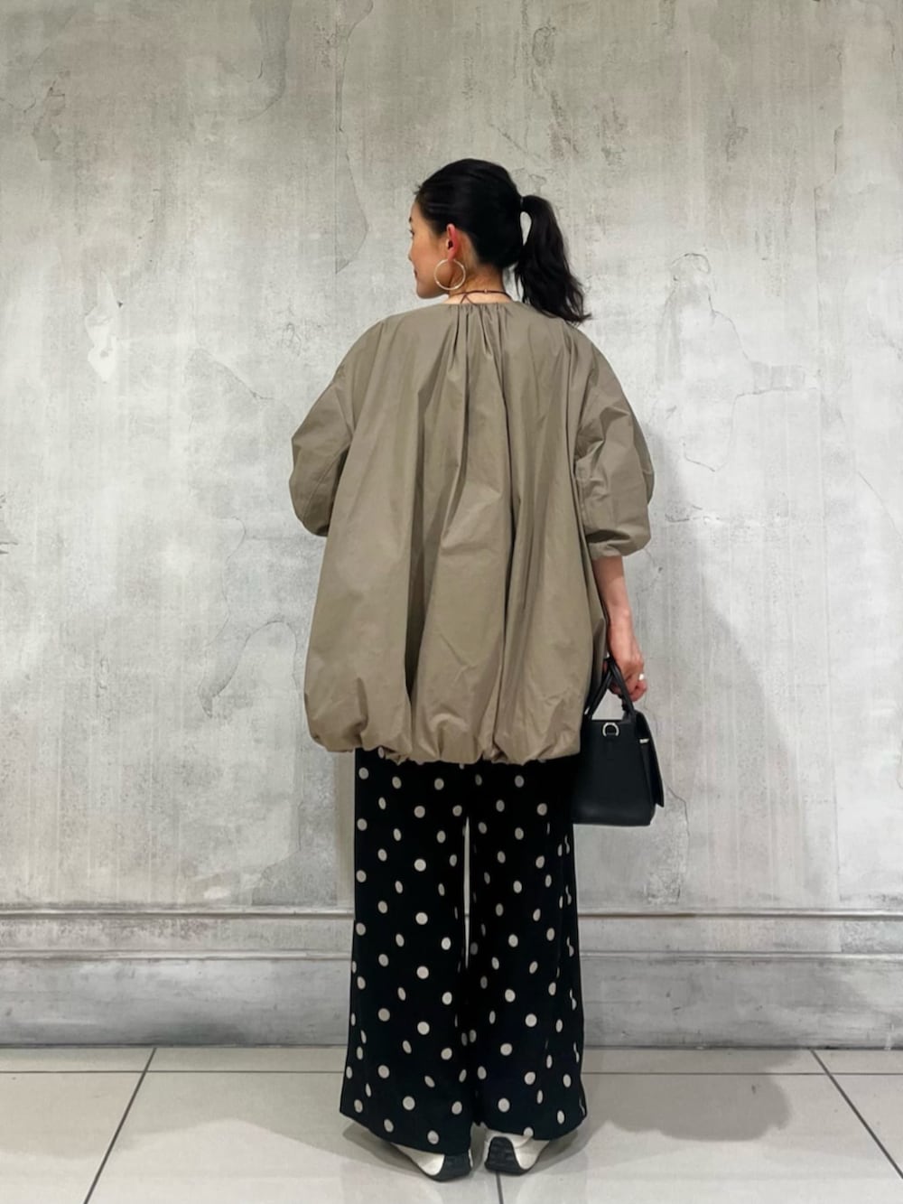 ブラック系のハンドバッグ、ブラック系のその他パンツ、ブラウン系のブルゾンを着用したレディースの春コーディネートの6枚目の写真