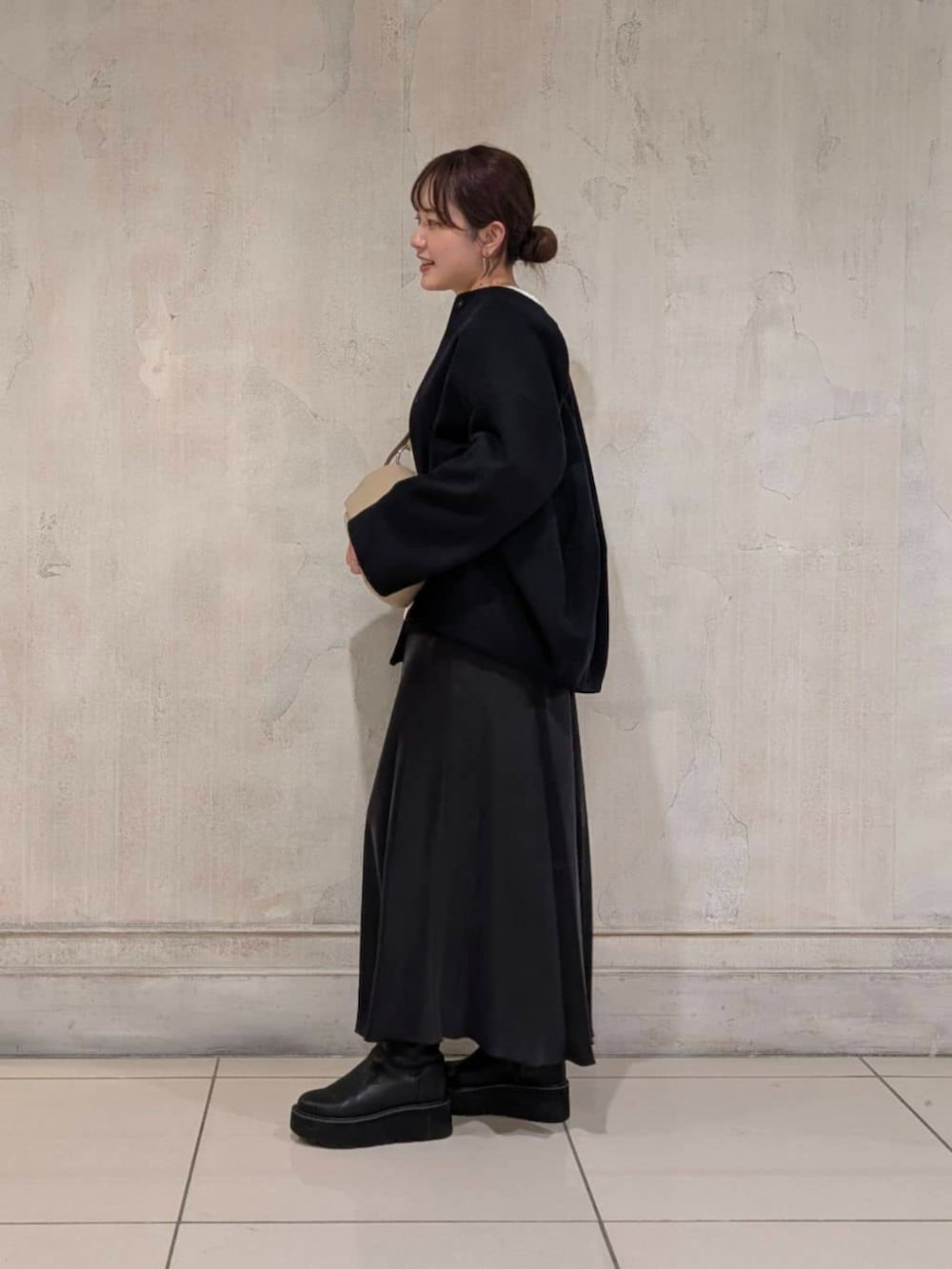 ブラック系のスカート、ブラック系のブーツ、ブルー系のノーカラーコートを着用したレディースの冬コーディネートの4枚目の写真