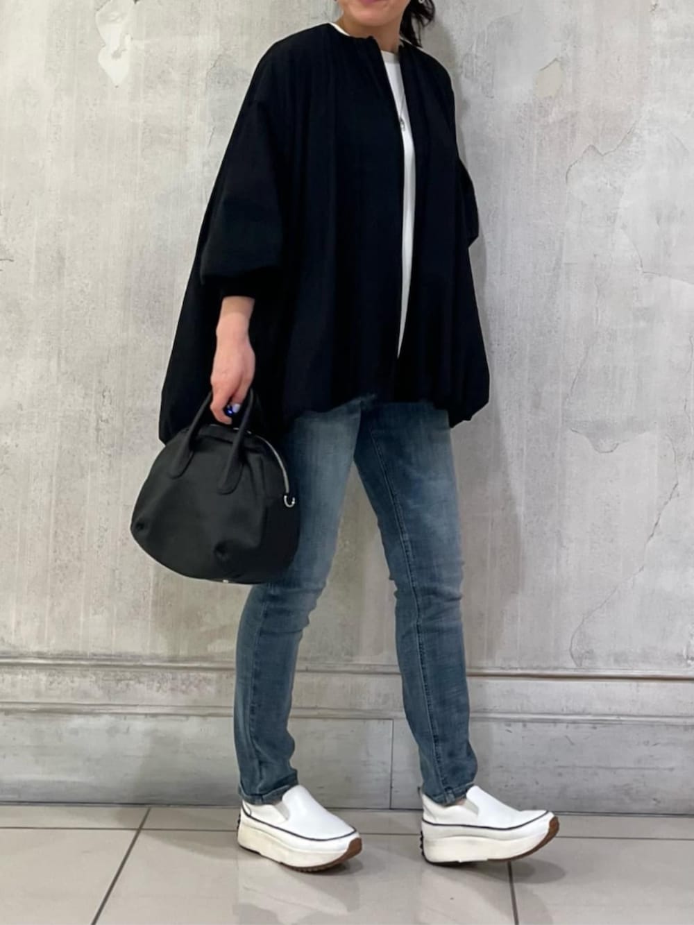 ホワイト系のスニーカー、ブルー系のデニムパンツ、ブラック系のボストンバッグを着用したレディースの冬コーディネートの8枚目の写真