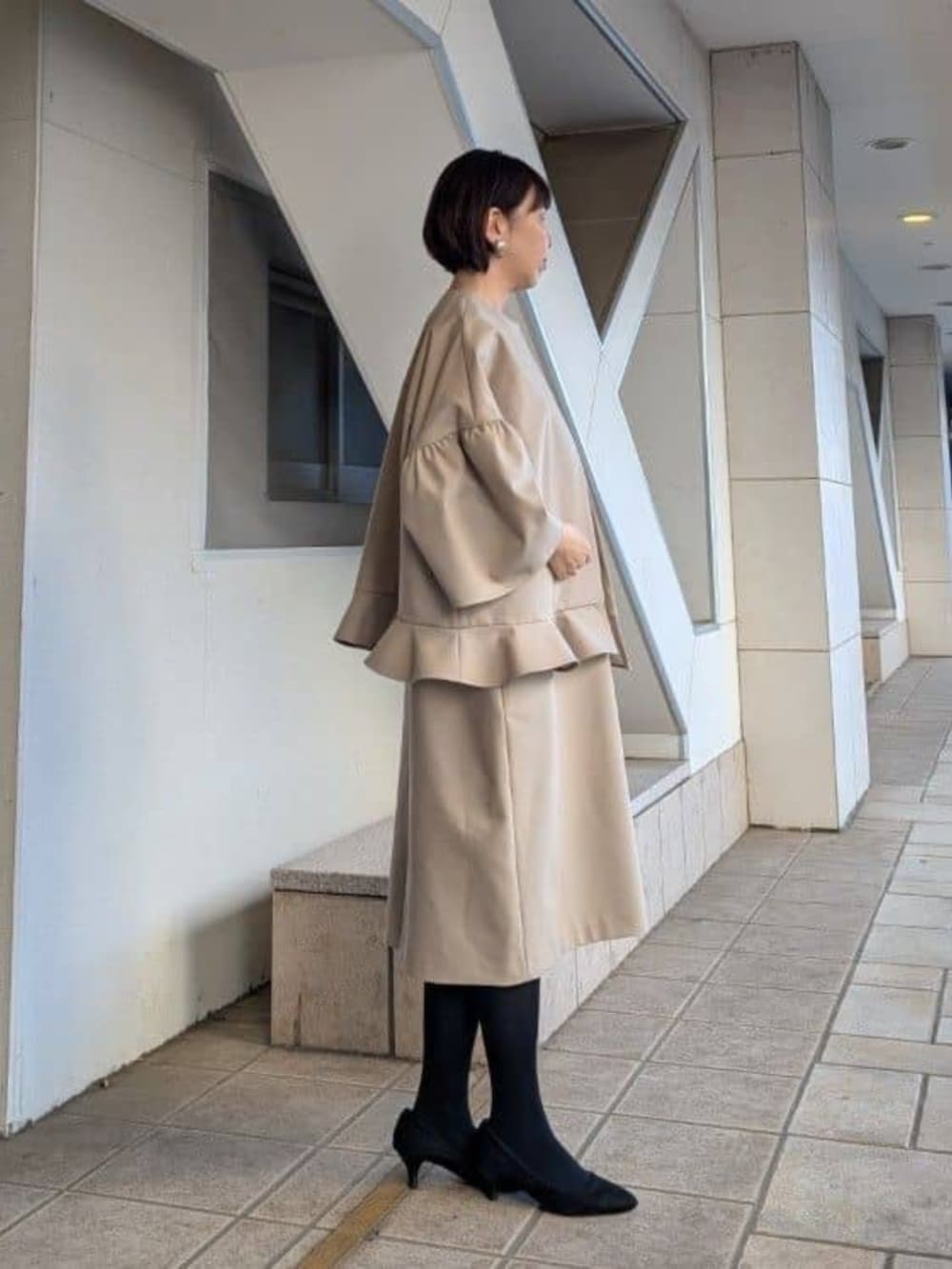 ブラック系のハンドバッグ、ベージュ系のワンピース、ベージュ系のその他アウターを着用したレディースの冬コーディネートの3枚目の写真