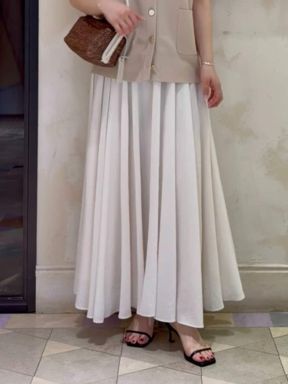 ホワイト系のスカート、ベージュ系のカーディガン/ボレロを着用したレディースの春コーディネートの8枚目の写真