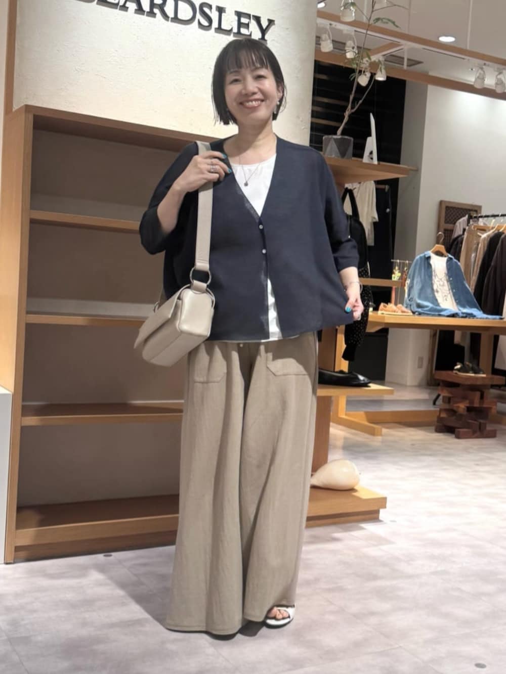 ベージュ系のその他パンツ、ベージュ系のショルダーバッグ、ブルー系のカーディガン/ボレロを着用したレディースの夏コーディネートの7枚目の写真