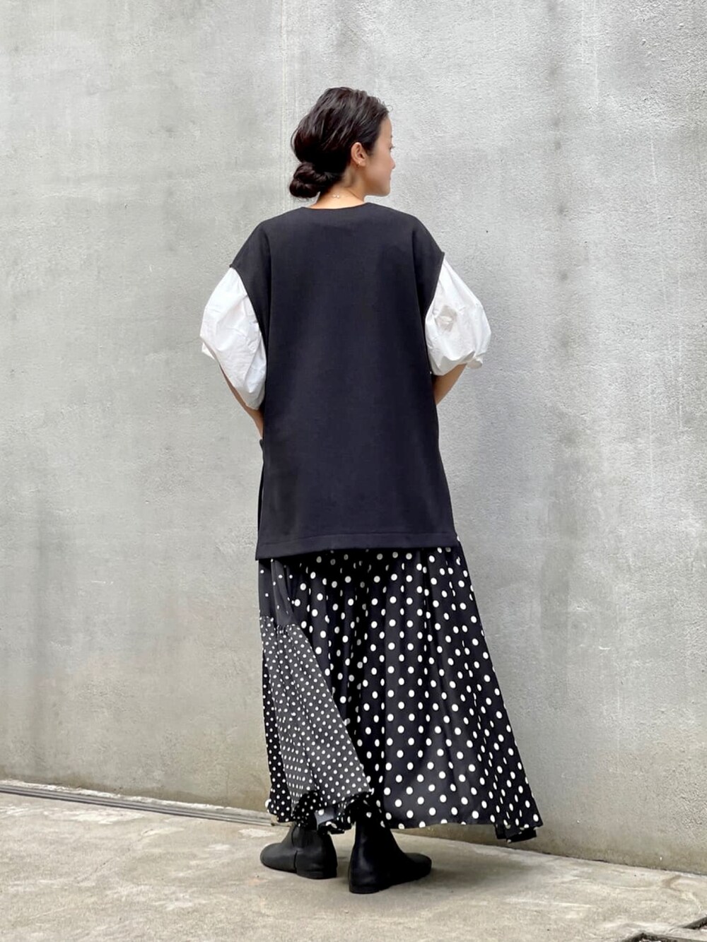 ブラック系のスカート、ホワイト系のシャツ/ブラウス、ブラック系のブーツを着用したレディースの夏コーディネートの2枚目の写真