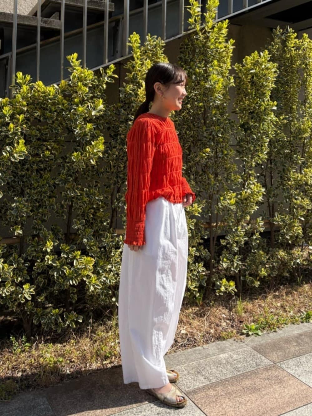 オレンジ系のシャツ/ブラウス、ホワイト系のその他パンツを着用したレディースの春コーディネートの4枚目の写真