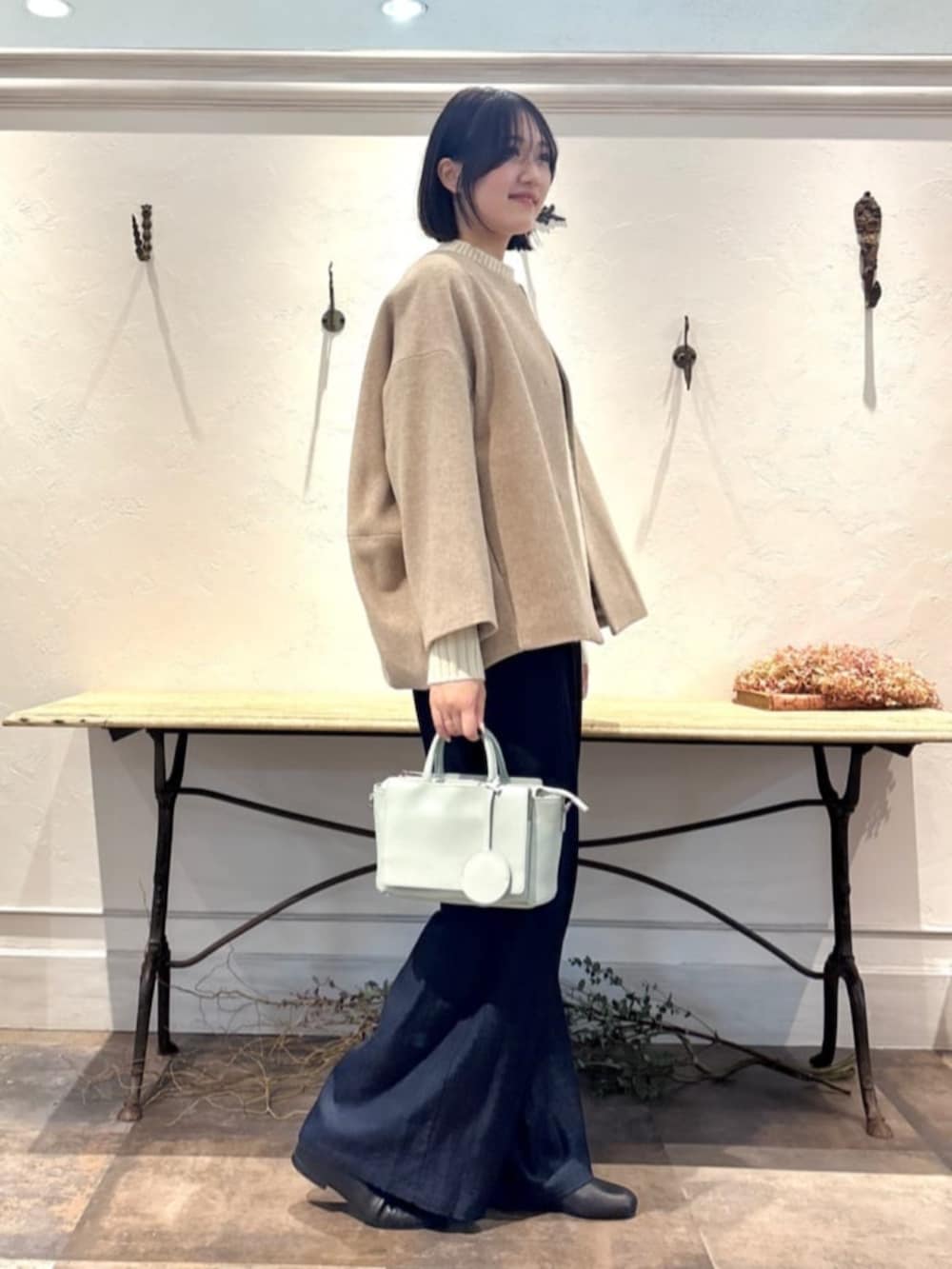 ブルー系のその他パンツ、グリーン系のハンドバッグ、ホワイト系のニット/セーターを着用したレディースの冬コーディネートの2枚目の写真