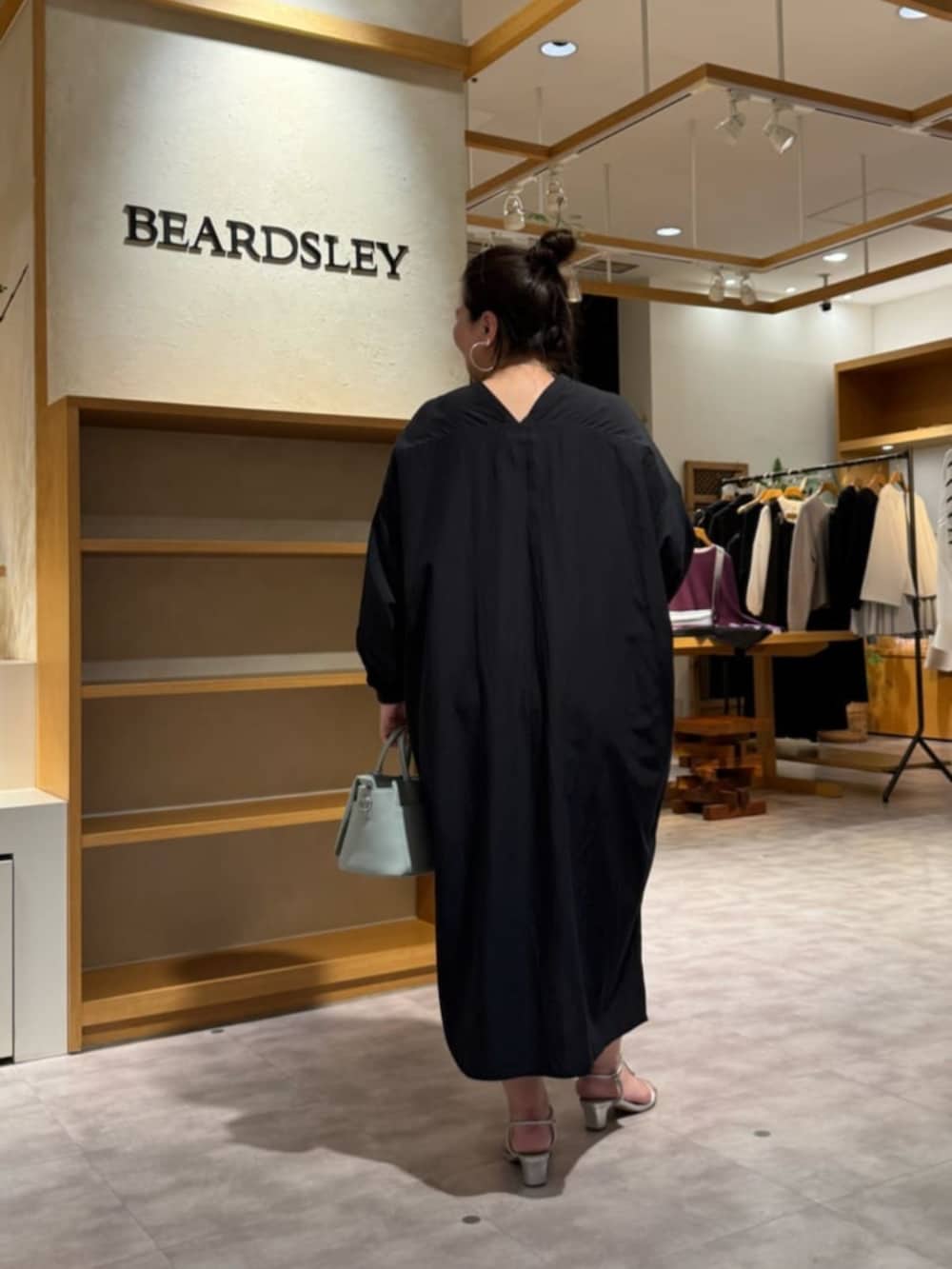 グリーン系のハンドバッグ、ブラック系のワンピースを着用したレディースの冬コーディネートの4枚目の写真