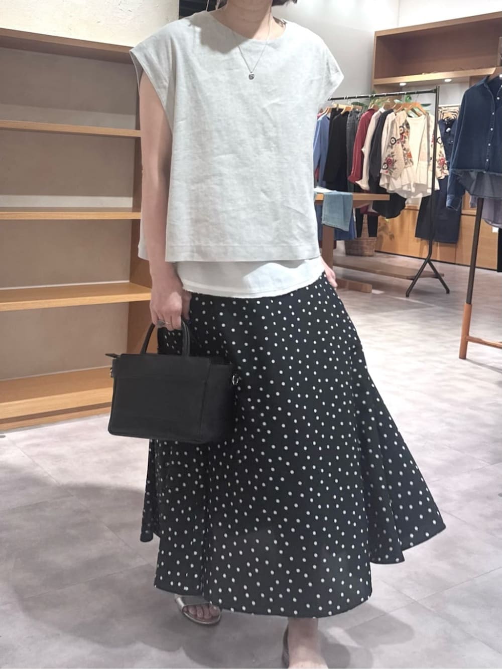 ブラック系のハンドバッグ、ブラック系のスカート、ベージュ系のシャツ/ブラウスを着用したレディースの春コーディネートの5枚目の写真